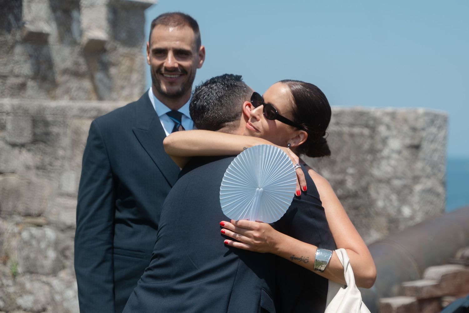 Multiple candid moments show two people hugging during a formal outdoor event.