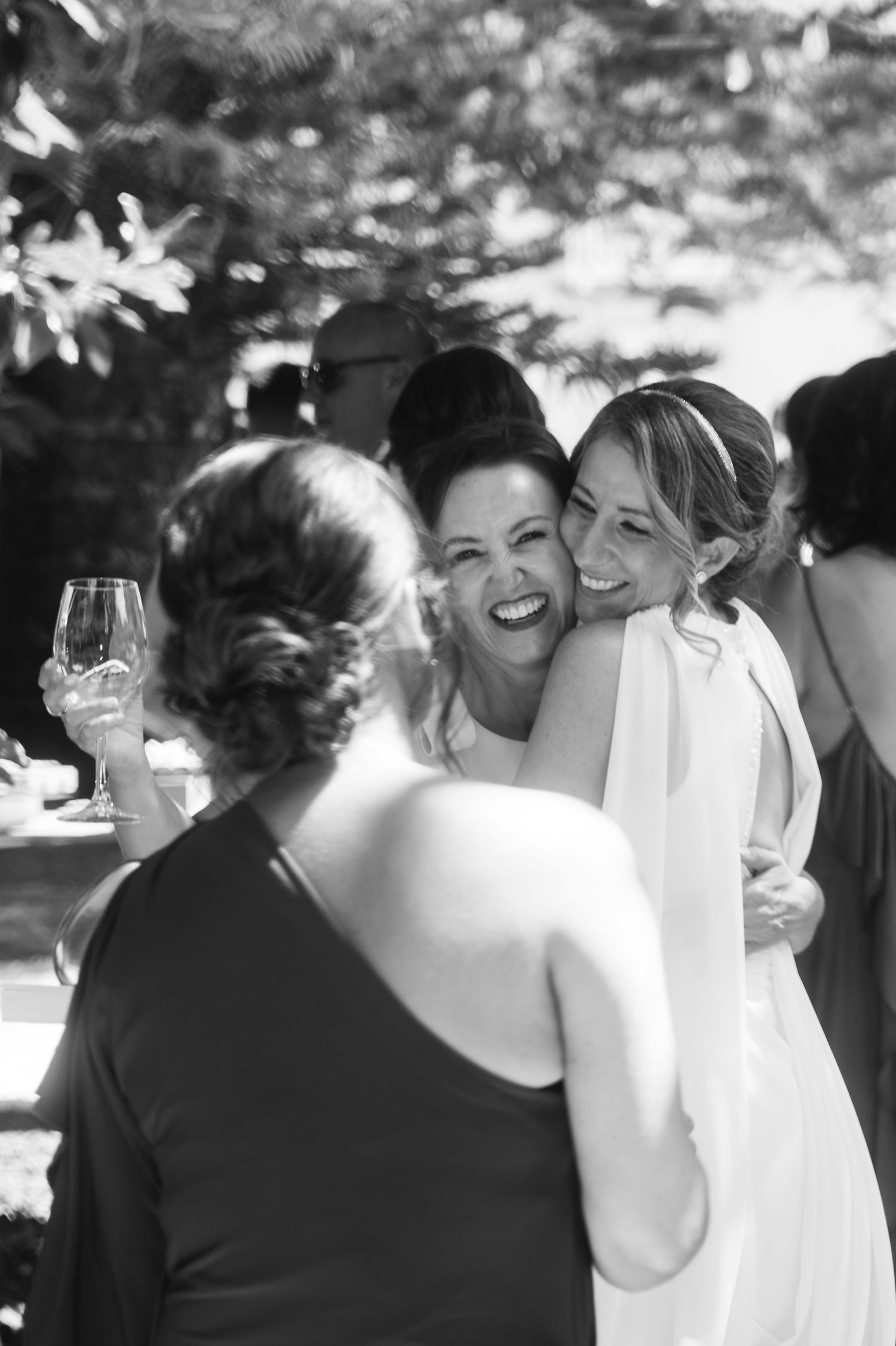 A group shares joyful laughter during an outdoor gathering under trees.