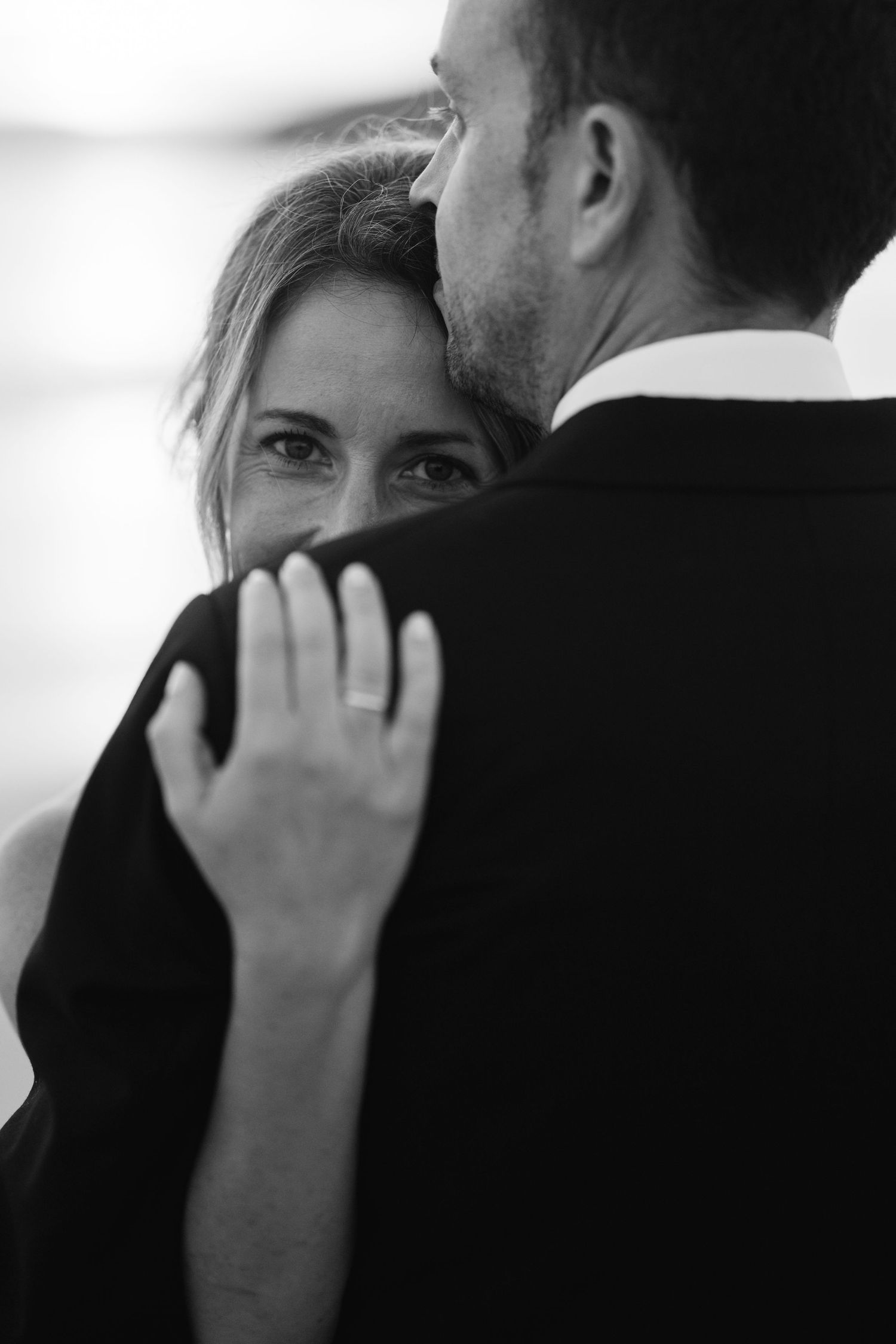 An intimate black and white portrait captures a tender moment between a couple on their wedding day.