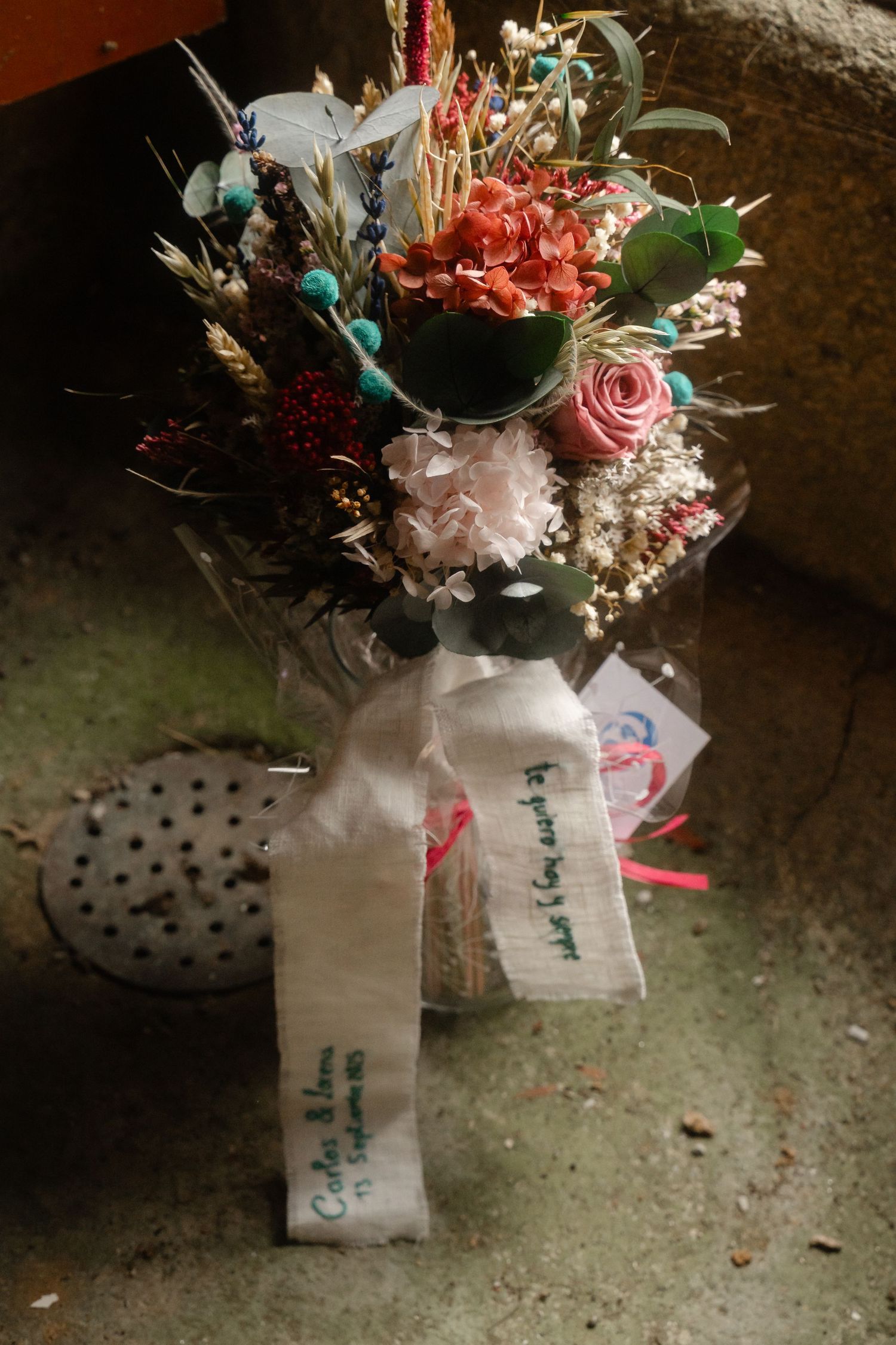Wedding bouquets with pink and white flowers arranged in white paper wrapping with handwritten tags.