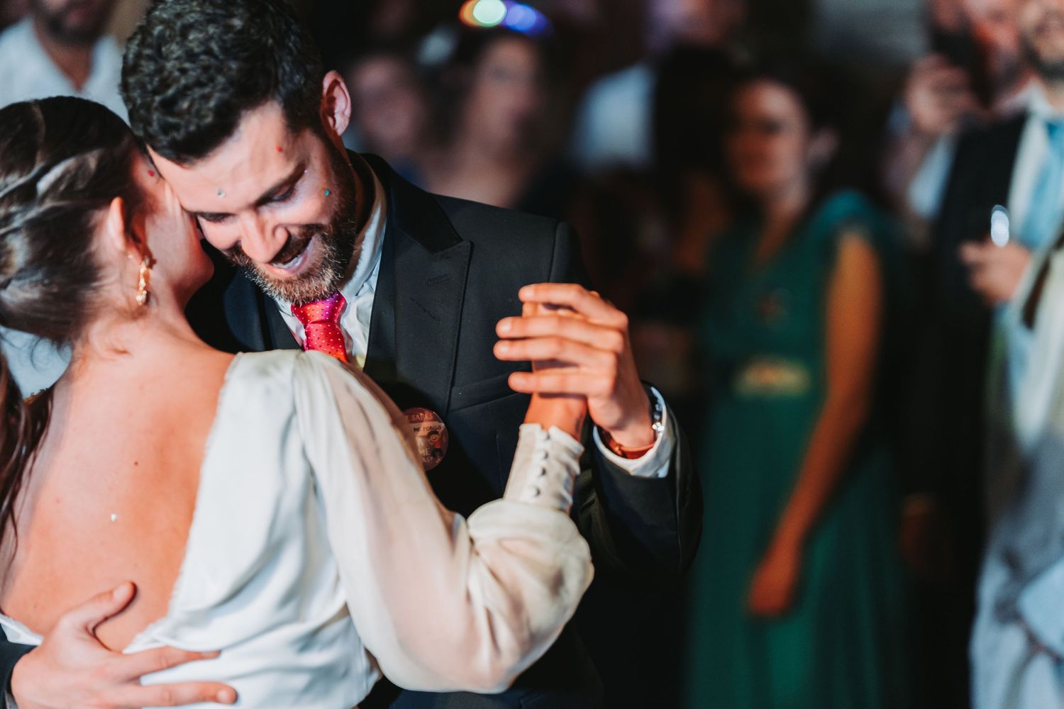 Wedding guests dance and celebrate together on a dimly lit dance floor during a reception party.