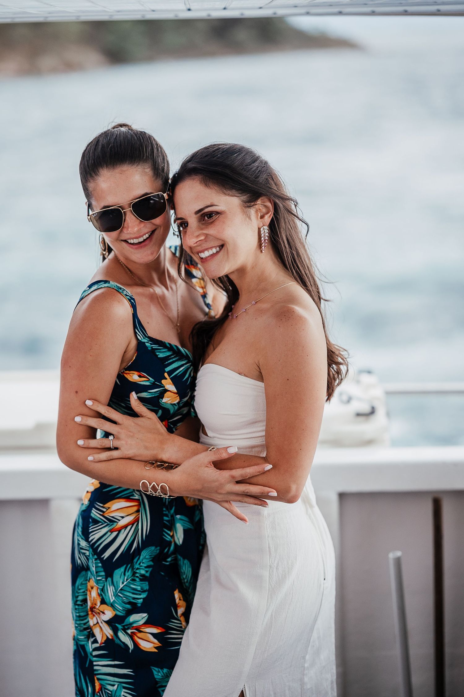 Friends sharing joyful moments at a waterfront celebration in tropical and white outfits.