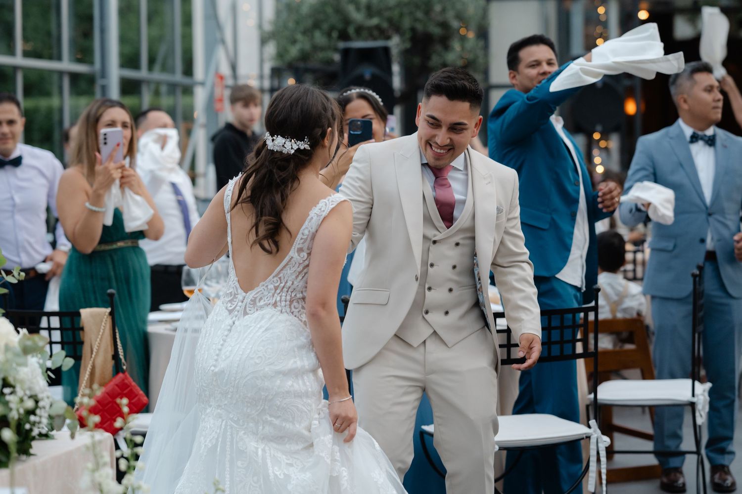 Wedding guests mingle and celebrate during an outdoor reception with elegant decor and natural lighting.