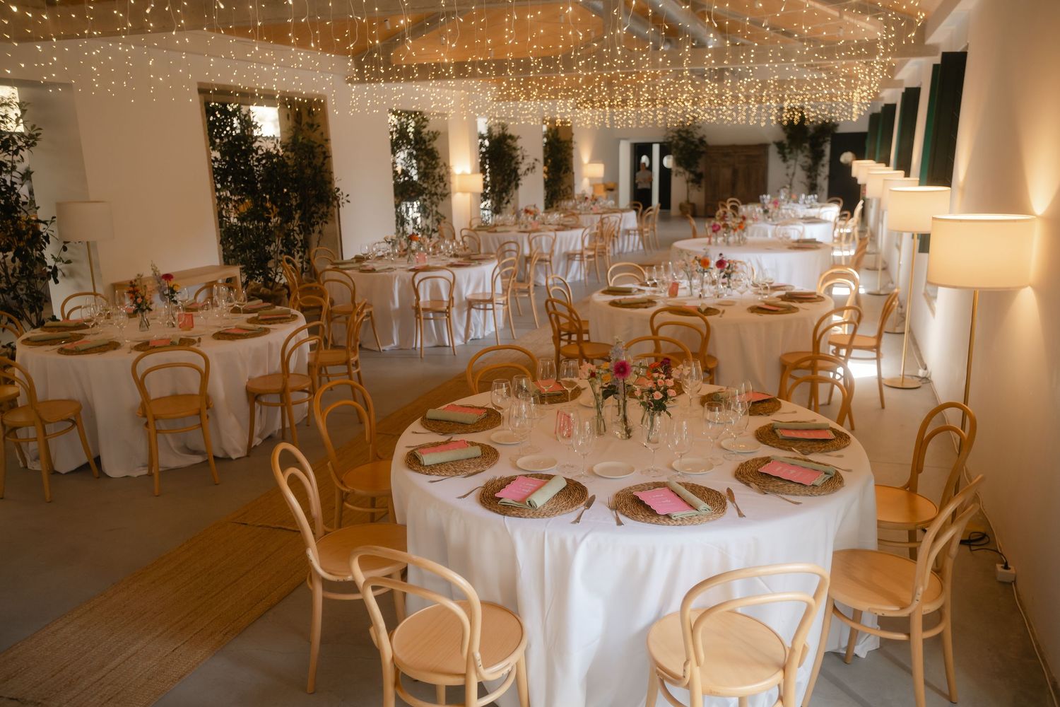 Elegant wedding reception venue with crystal chandeliers, white linens, and gold chairs set for a formal celebration.