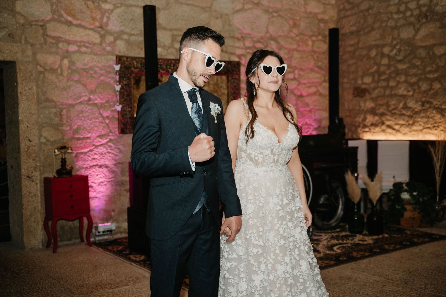 Elegant wedding reception in a historic stone-walled venue with decorative lighting and formal attire.