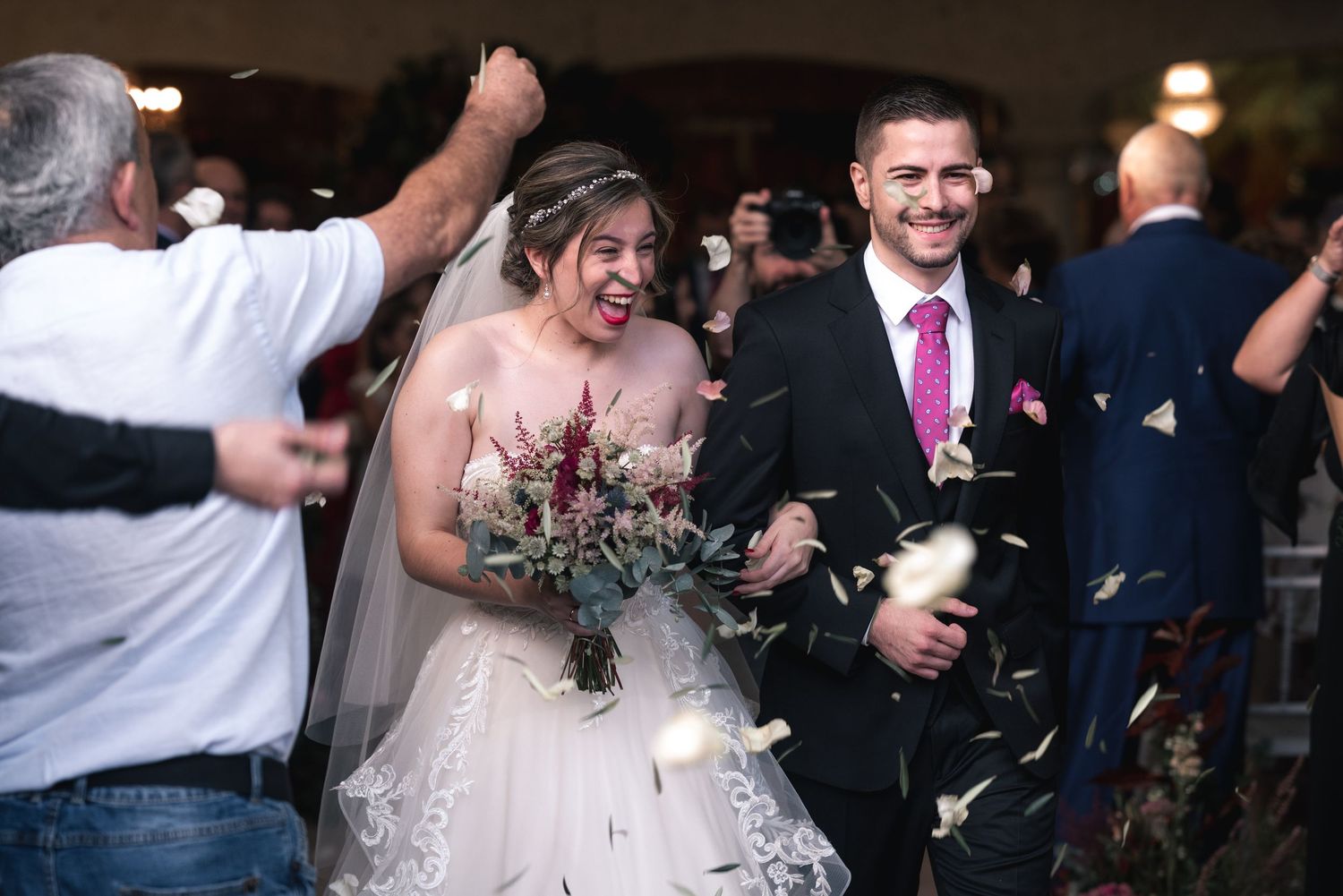 Wedding guests dance and celebrate together on a dimly lit dance floor during an evening reception.