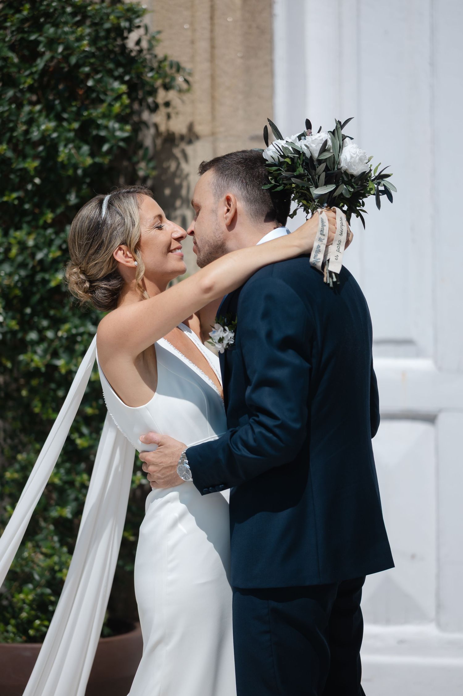 A romantic wedding moment captured in a series of intimate poses against a white column and greenery backdrop.
