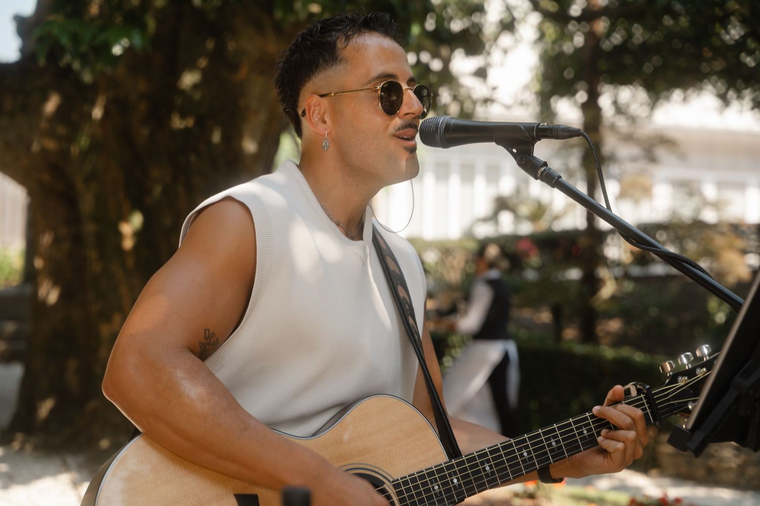 Musicians perform with guitars at an outdoor wedding reception.