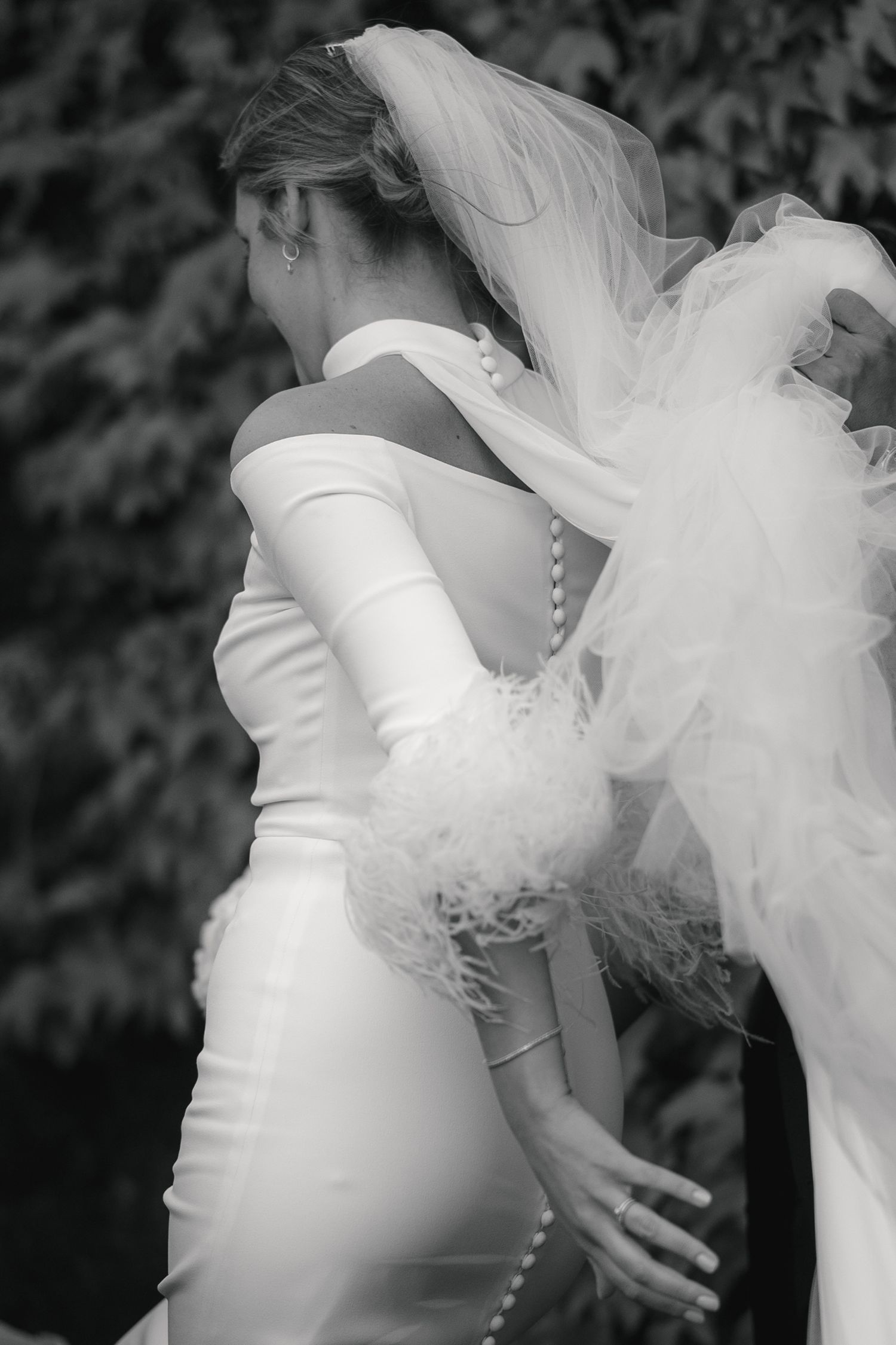 A black and white wedding photo sequence showing close-up details of a bride's white dress and flowing veil.