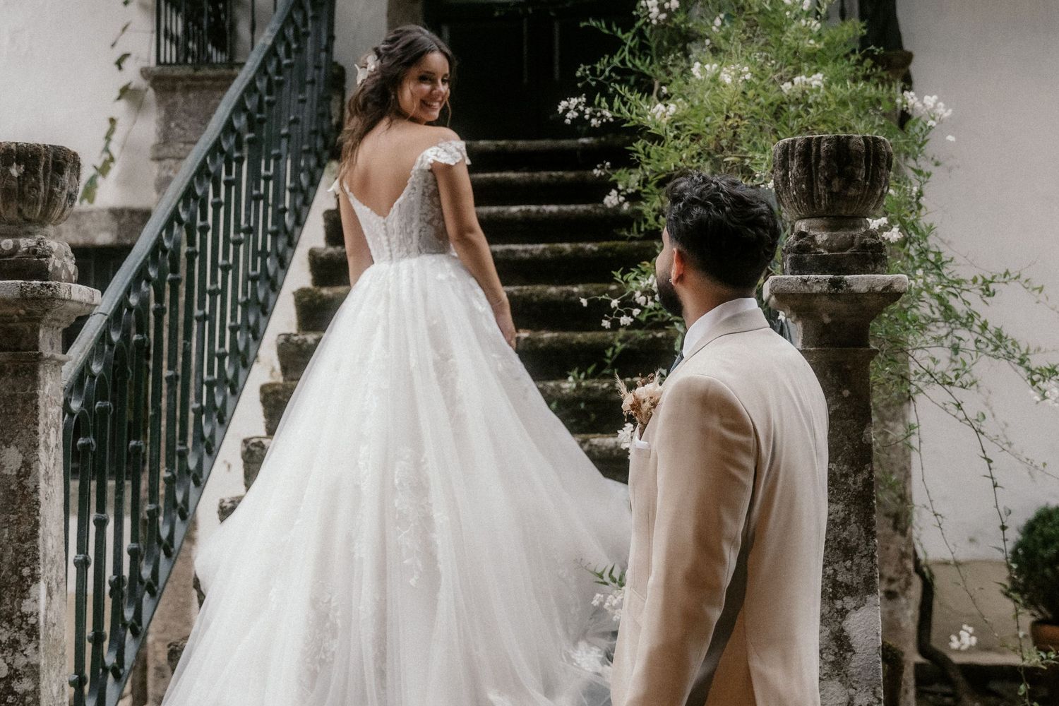 A romantic wedding scene on stone steps with a flowing white ballgown dress and tan suit.