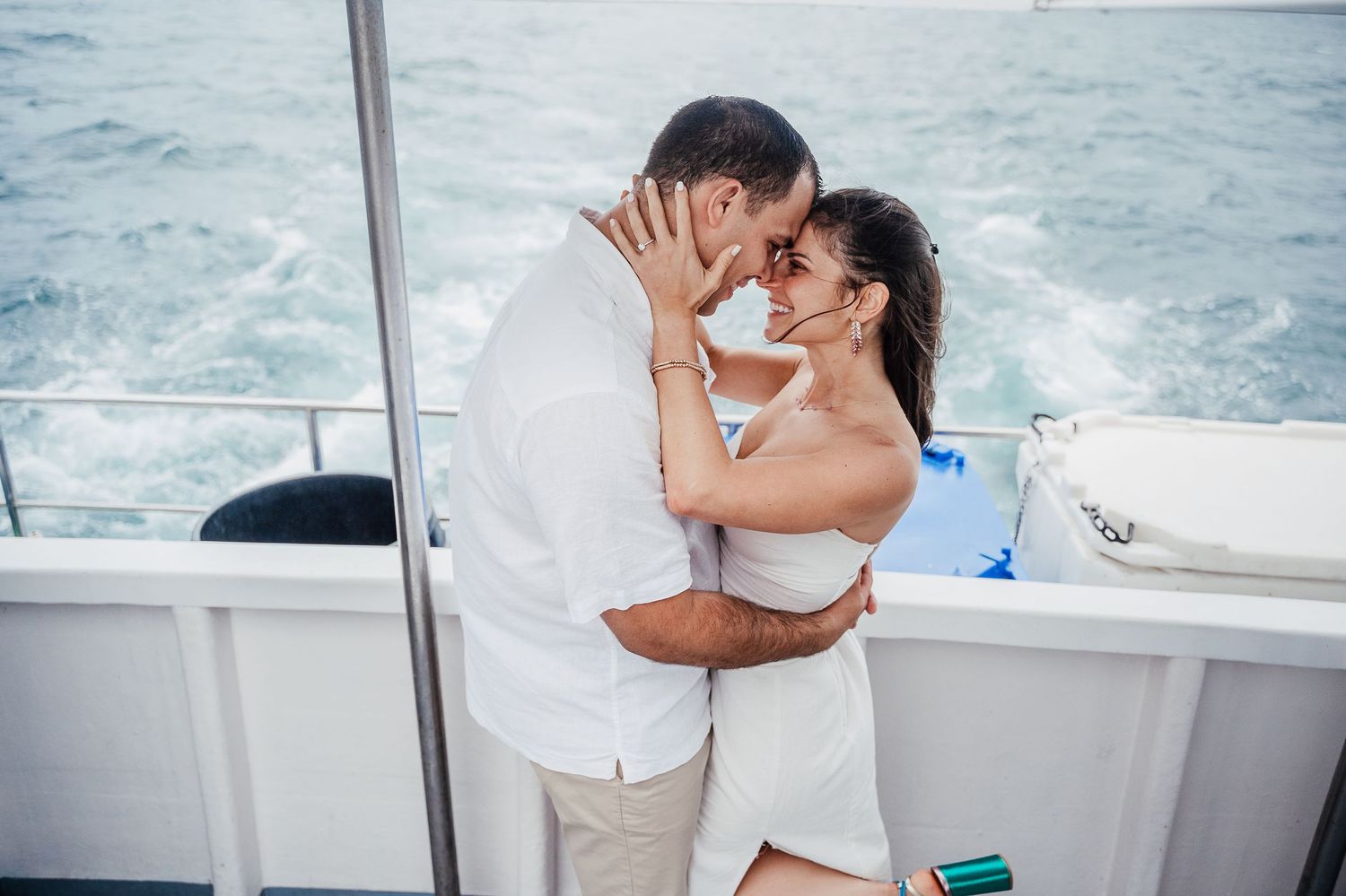 A romantic couple shares an intimate moment while sailing on a boat in the ocean.