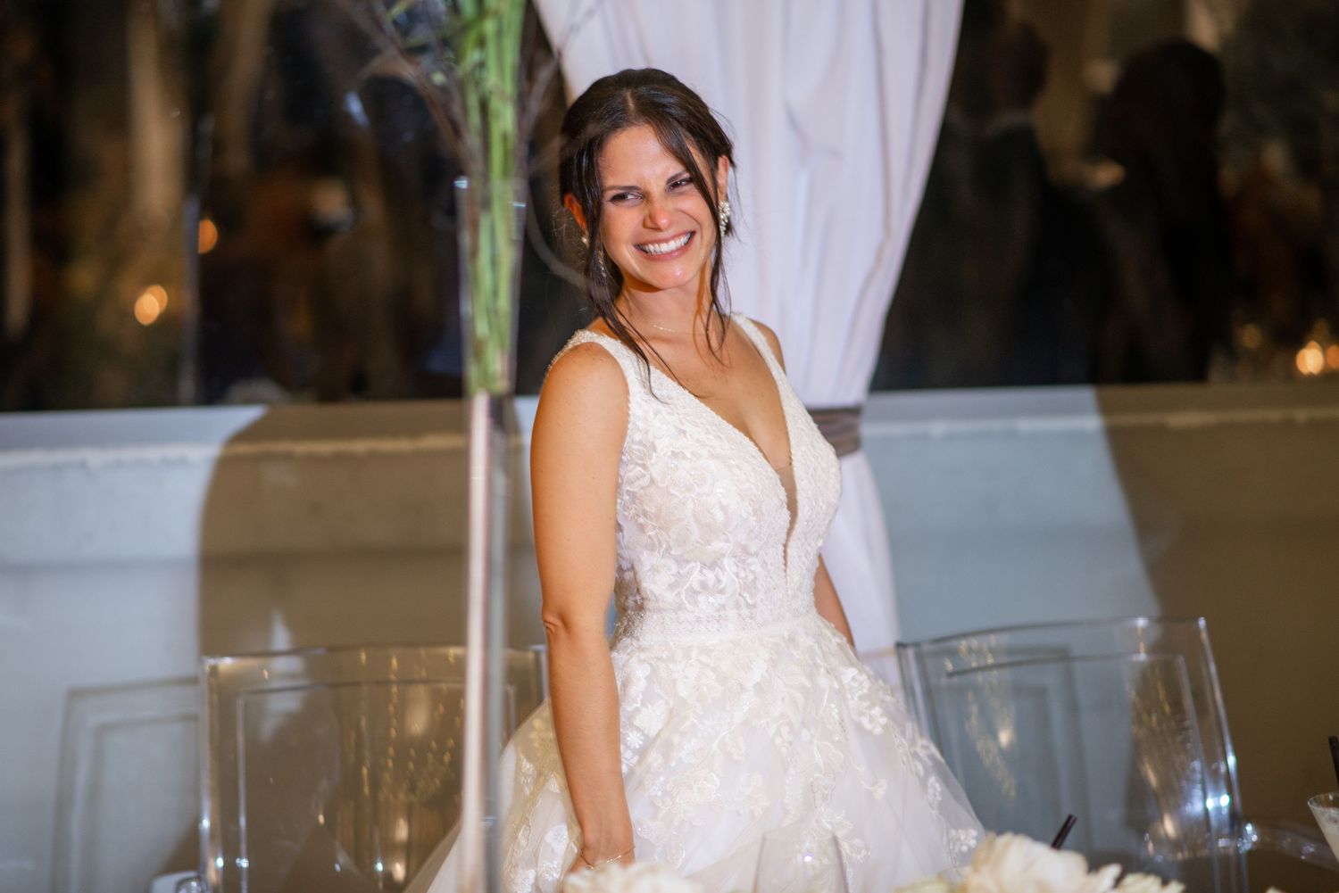 Elegant wedding reception venue with white decor and table settings under warm lighting.