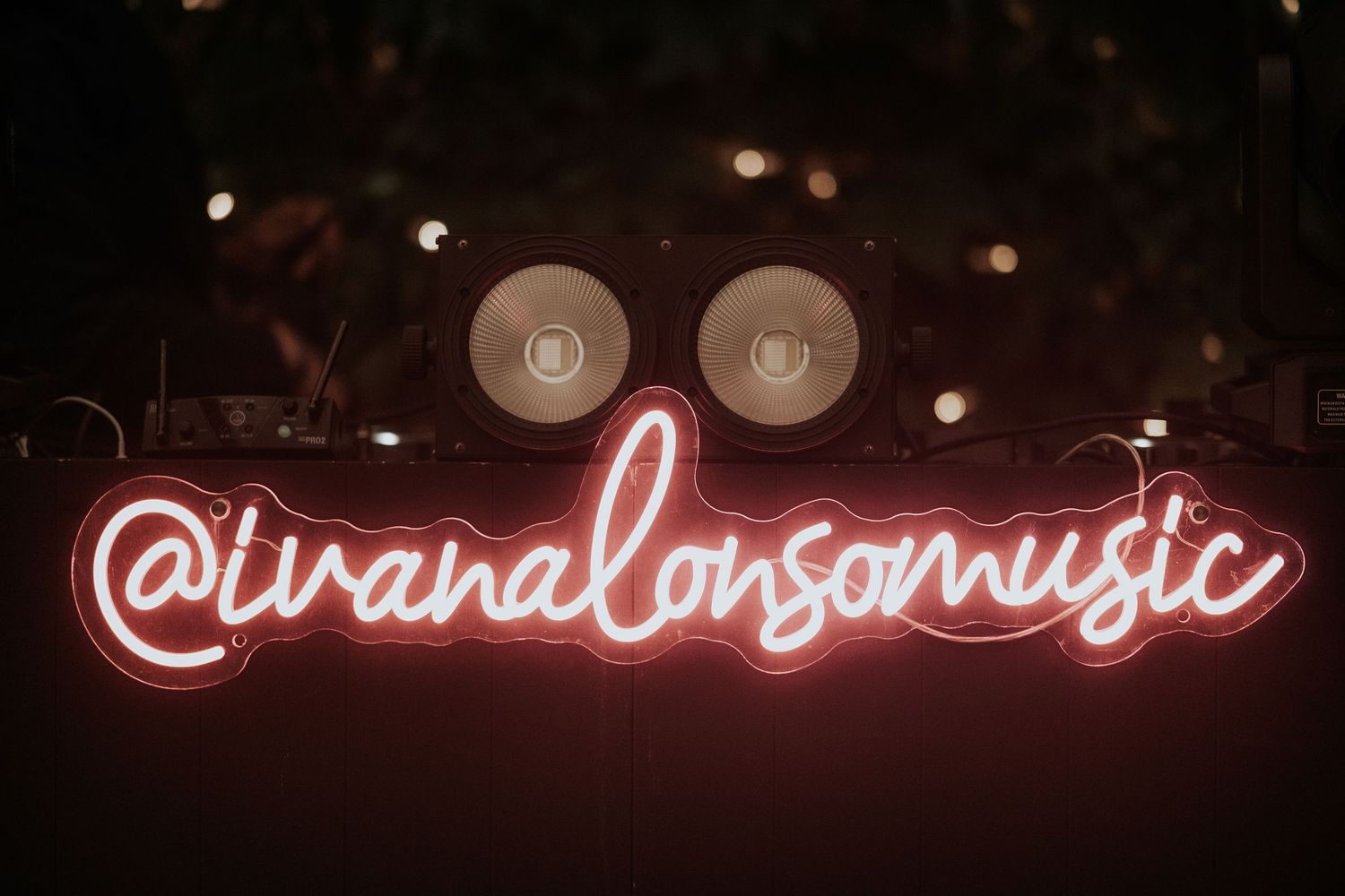 A glowing red neon sign illuminates a dark room with decorative lighting elements in the background.