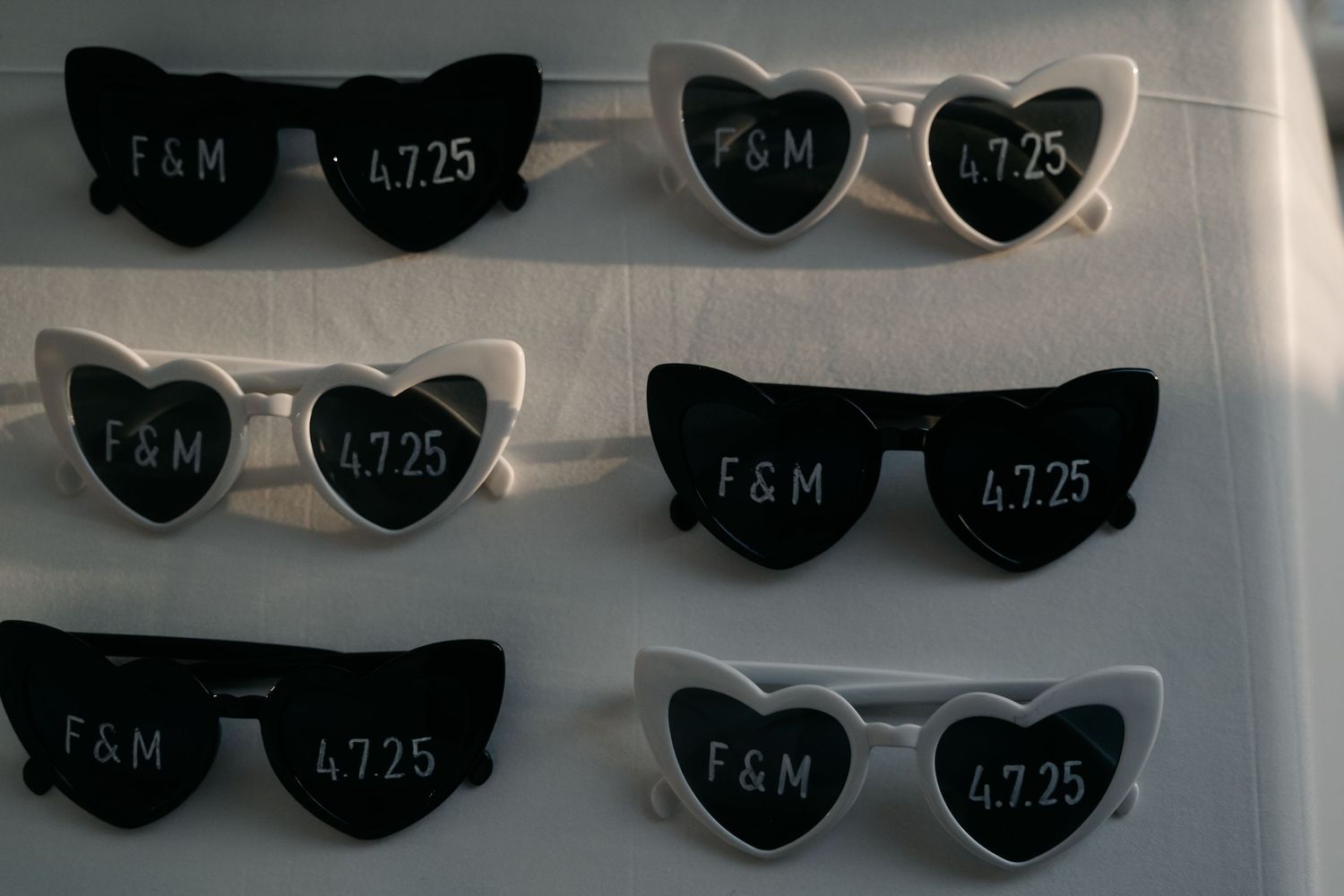 Heart-shaped sunglasses arranged in rows on a white surface with price tags attached.