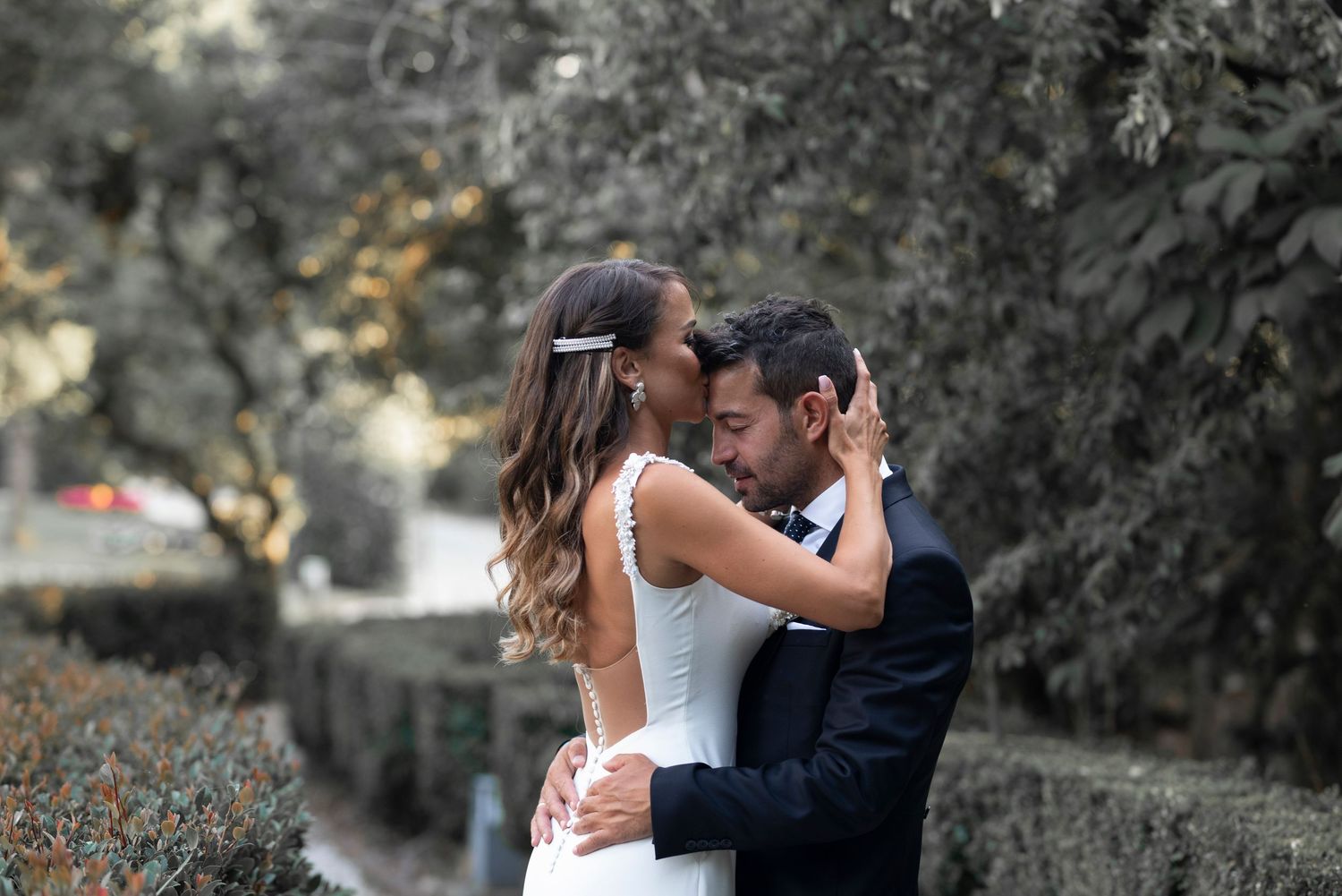 A romantic couple embraces in an outdoor setting with moody lighting and natural scenery.