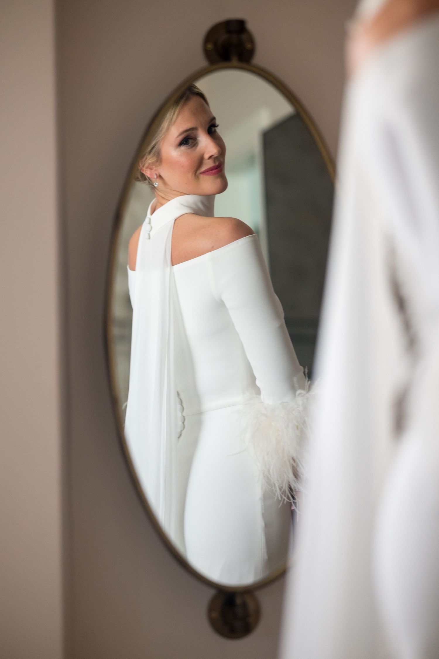 Artistic reflection of a white wedding dress in an ornate vintage mirror.
