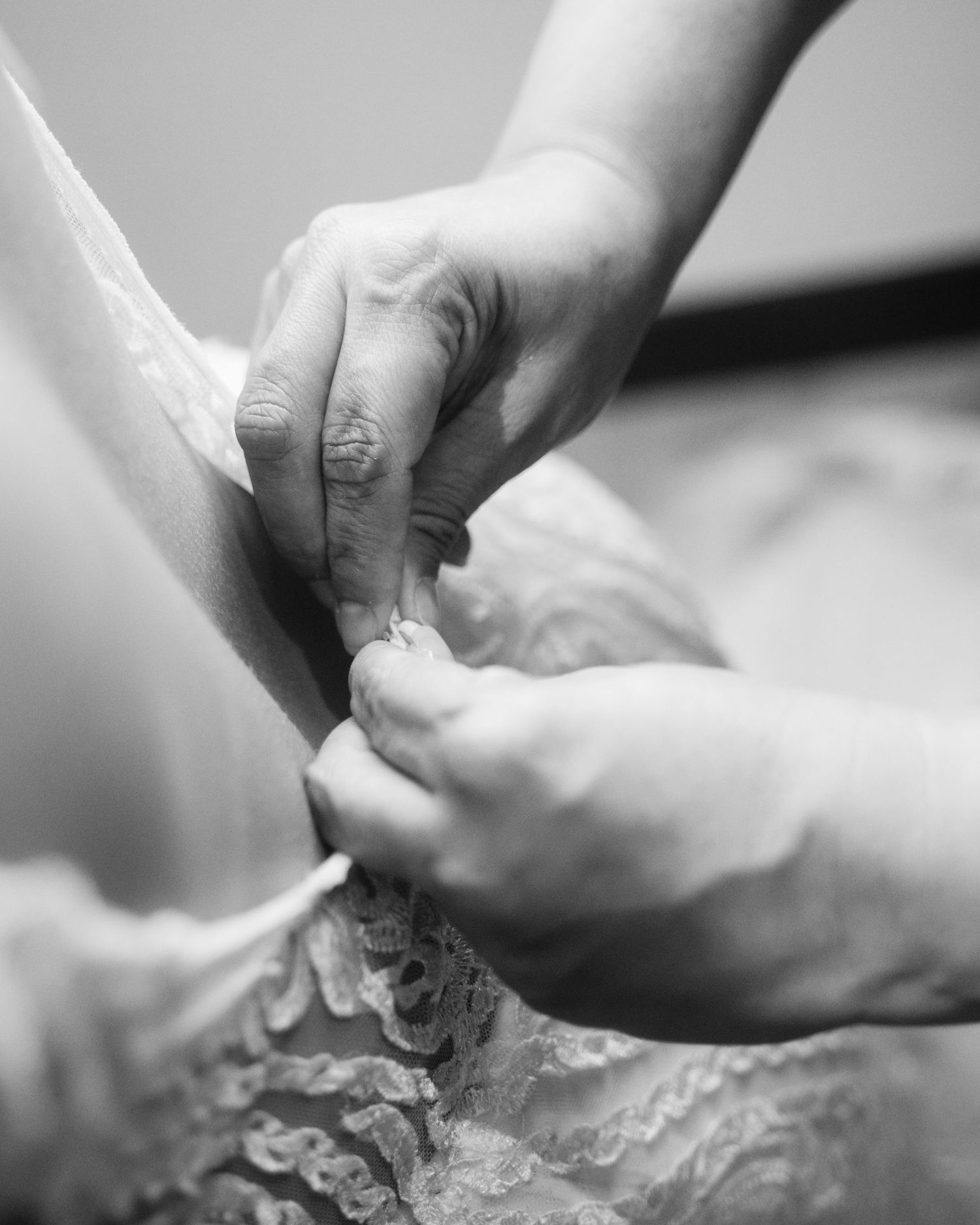 Black and white close-up of hands kneading and shaping dough on a floured surface.