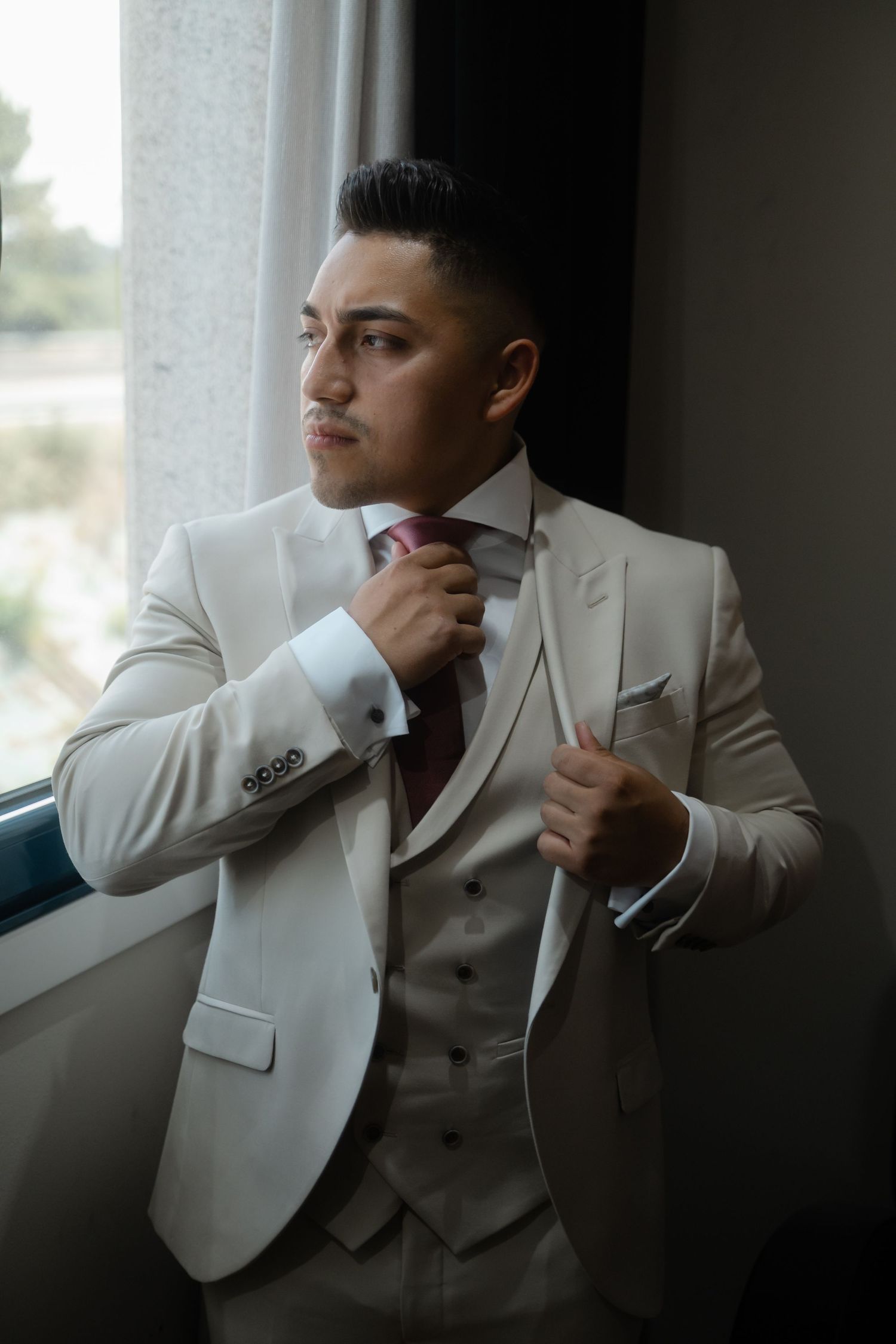 White suit jacket photographed in moody lighting against a window backdrop creating a dramatic silhouette.