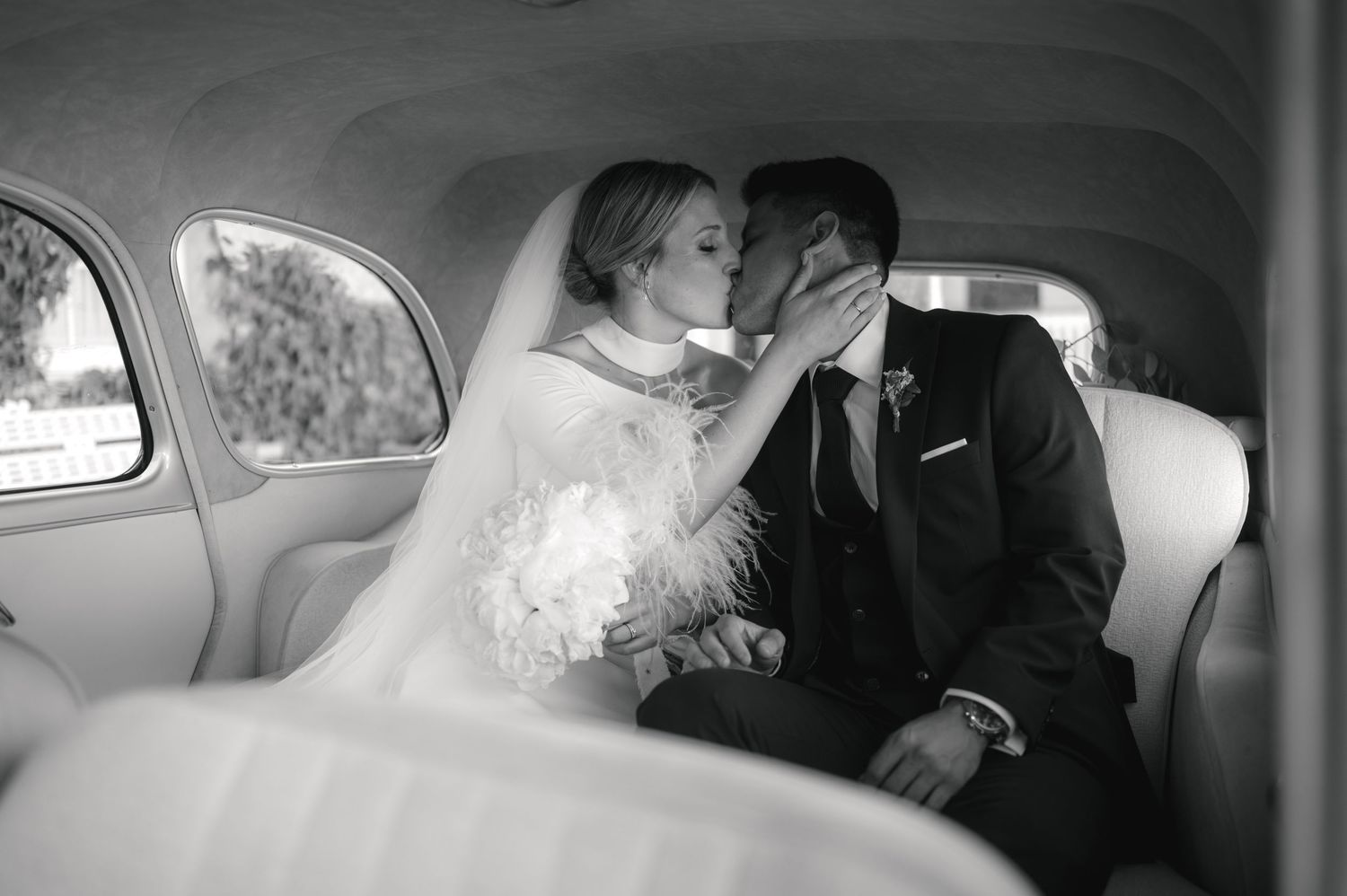 Romantic black and white photo series of a couple embracing in the back seat of a car.