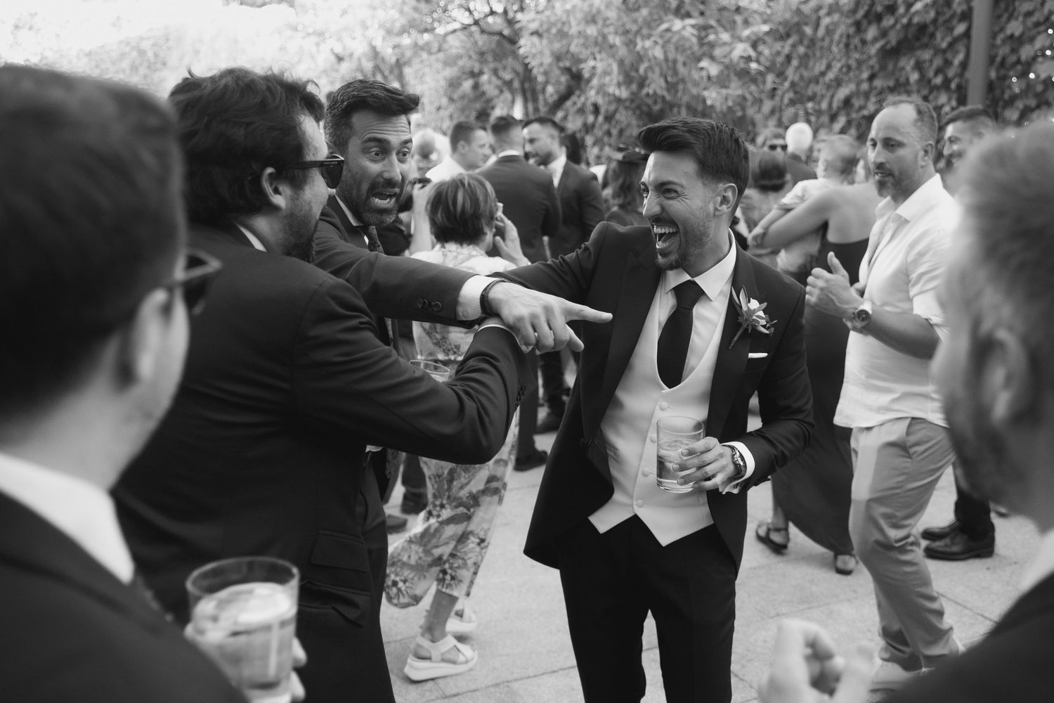 Wedding party dancing and celebrating together at an outdoor reception venue.