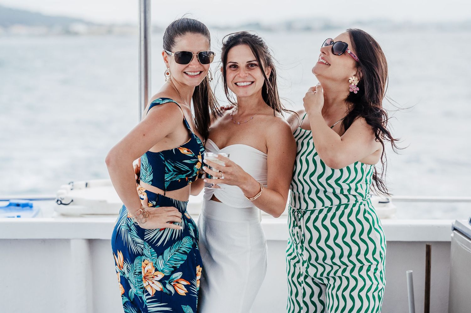 People celebrating at a waterfront party wearing tropical print and green patterned dresses.