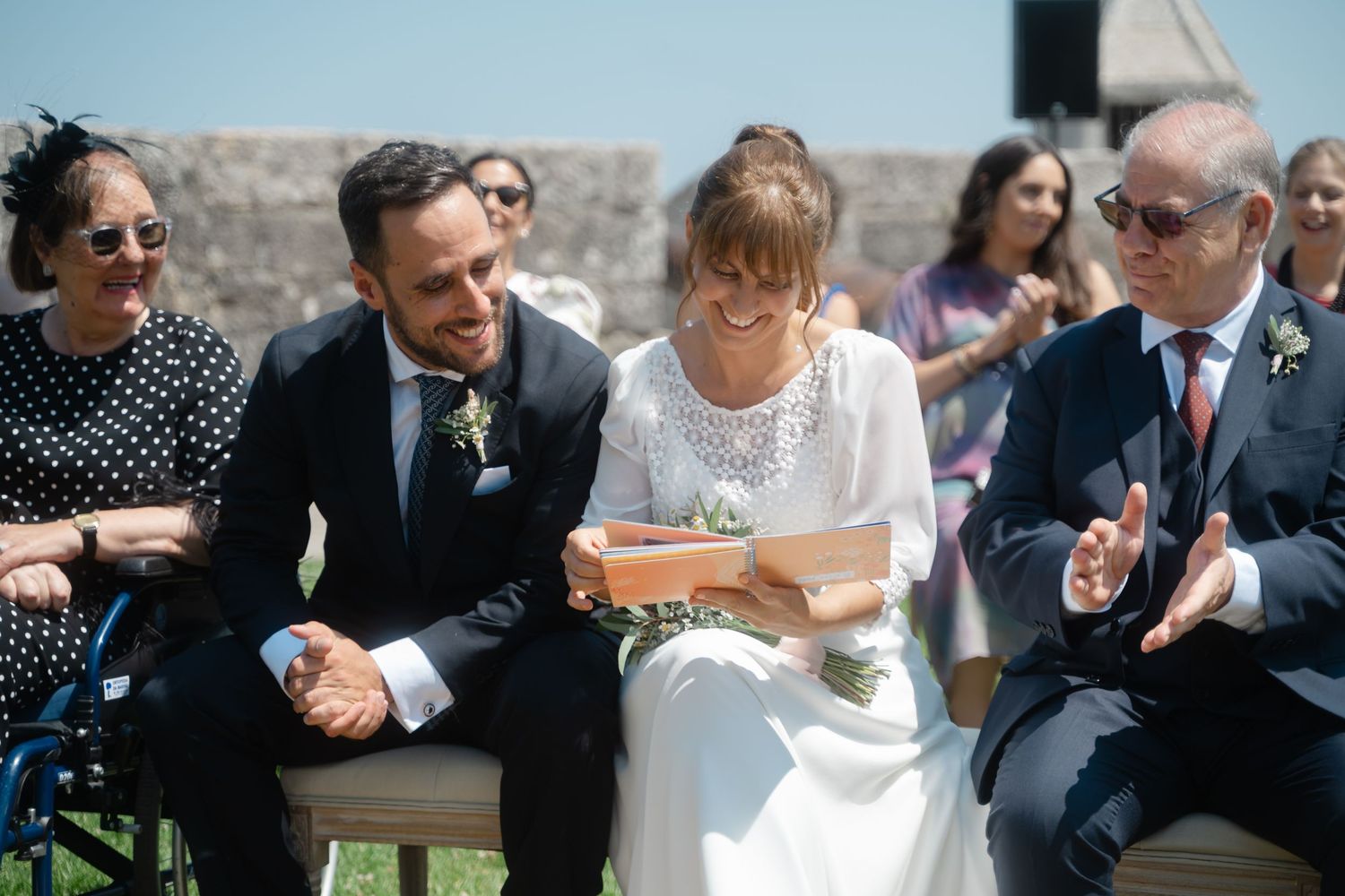 Wedding ceremony guests gathered outdoors on a sunny day.