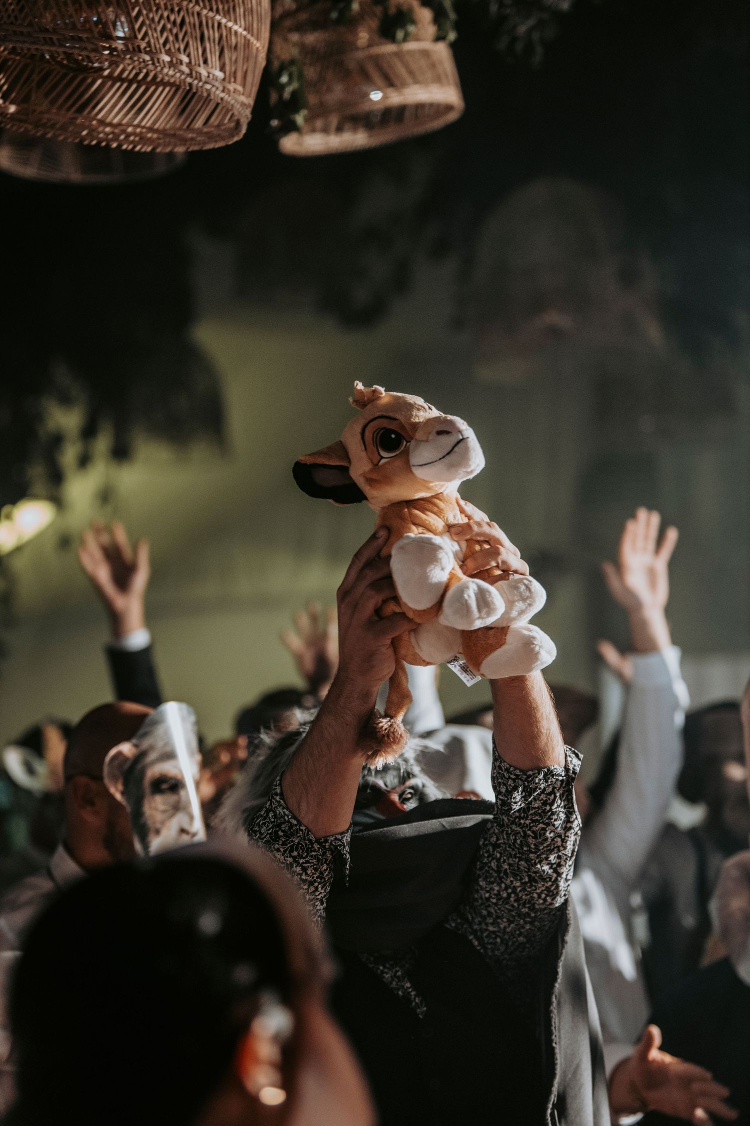 Crowd at a wedding reception holding up plush toys in celebration.