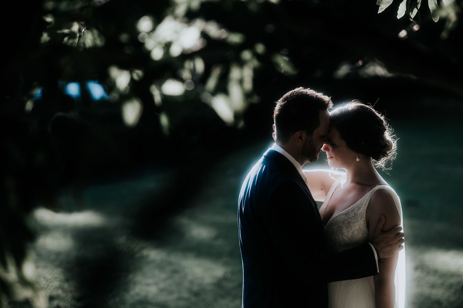 A romantic silhouette of a couple embracing in a dreamy outdoor setting with soft bokeh lighting effects.