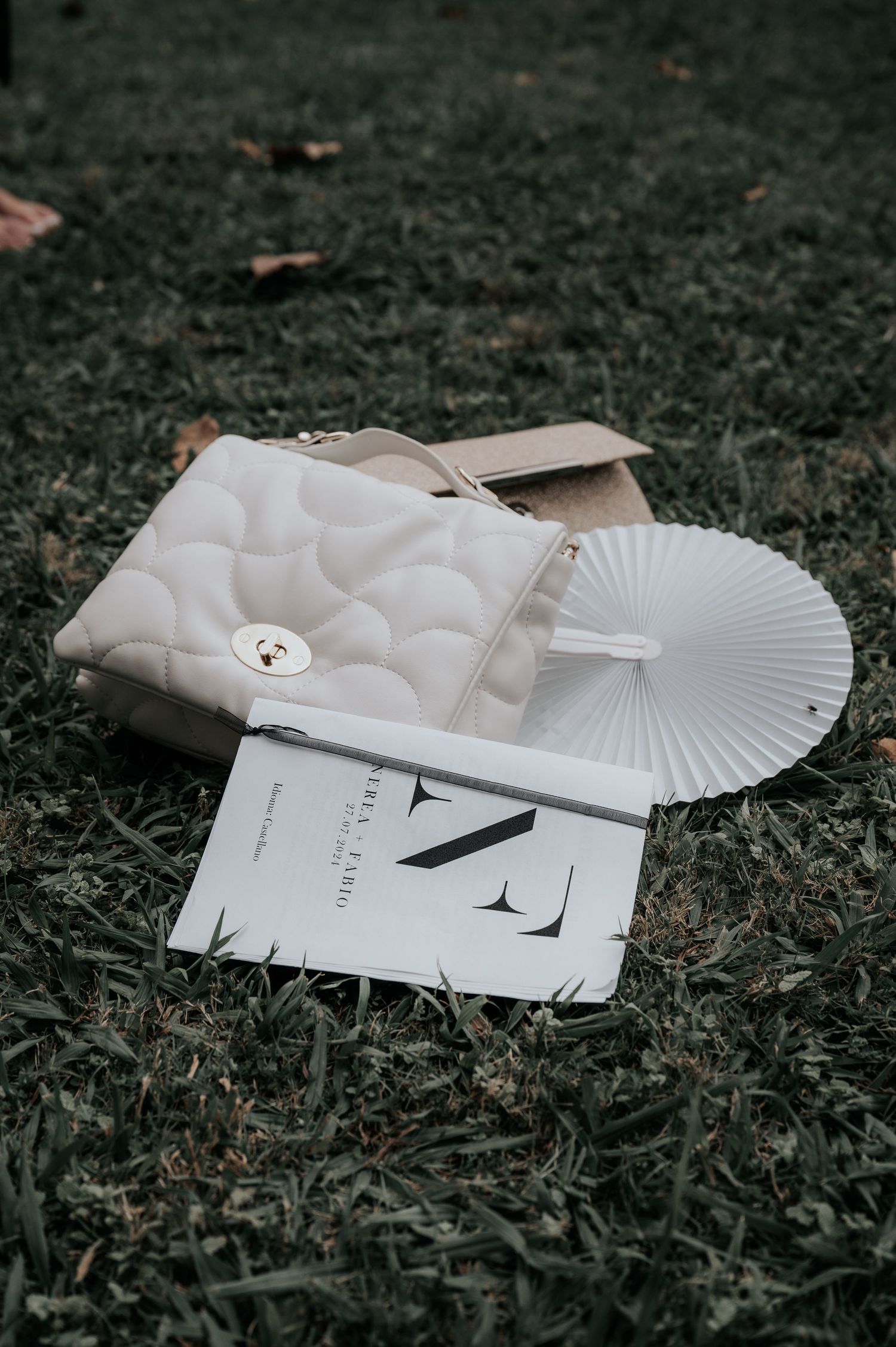 White paper fans and wedding stationery lay artistically arranged on dark ground in moody lighting.