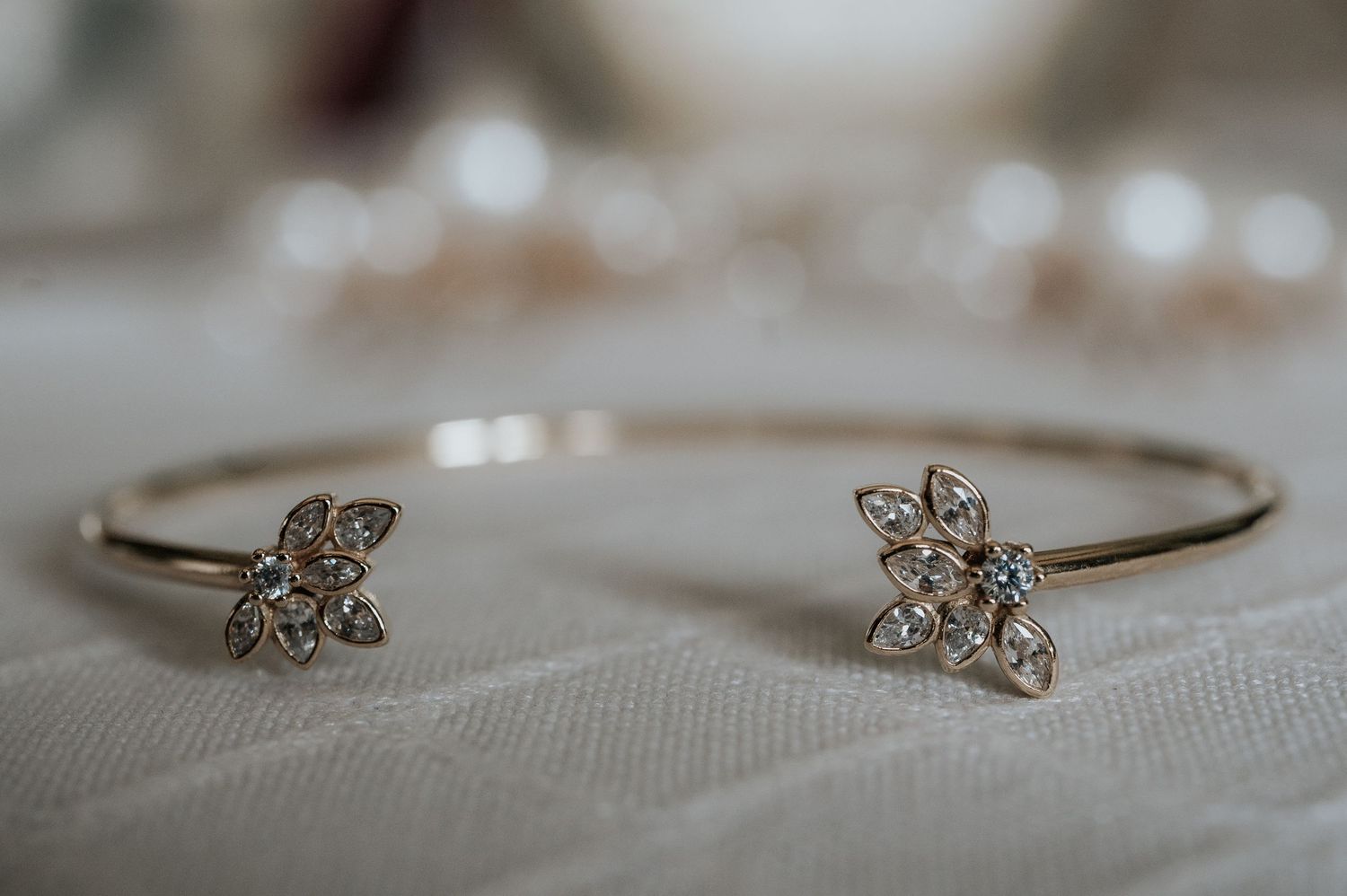 Delicate silver bracelet with small crystal butterfly charm displayed on textured white fabric.