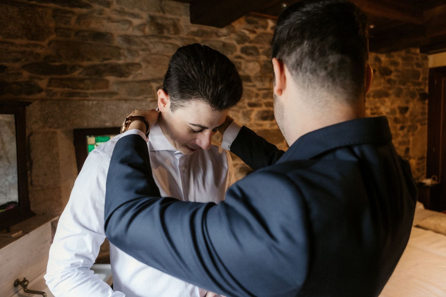 Two people in formal attire sharing an intimate dance moment in a dimly lit rustic venue with brick walls.