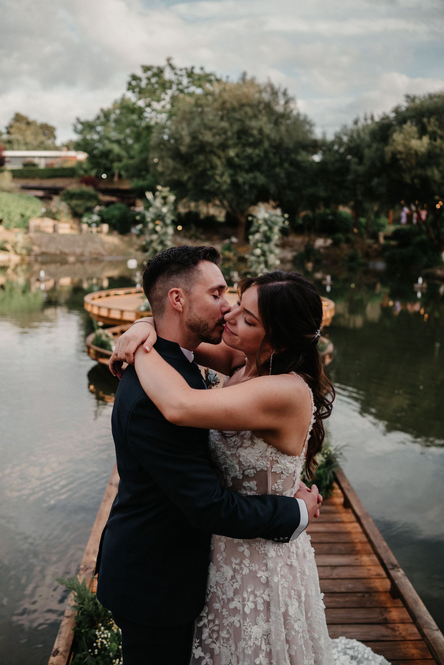 A romantic couple shares tender moments on a wooden dock by a serene lake during sunset.