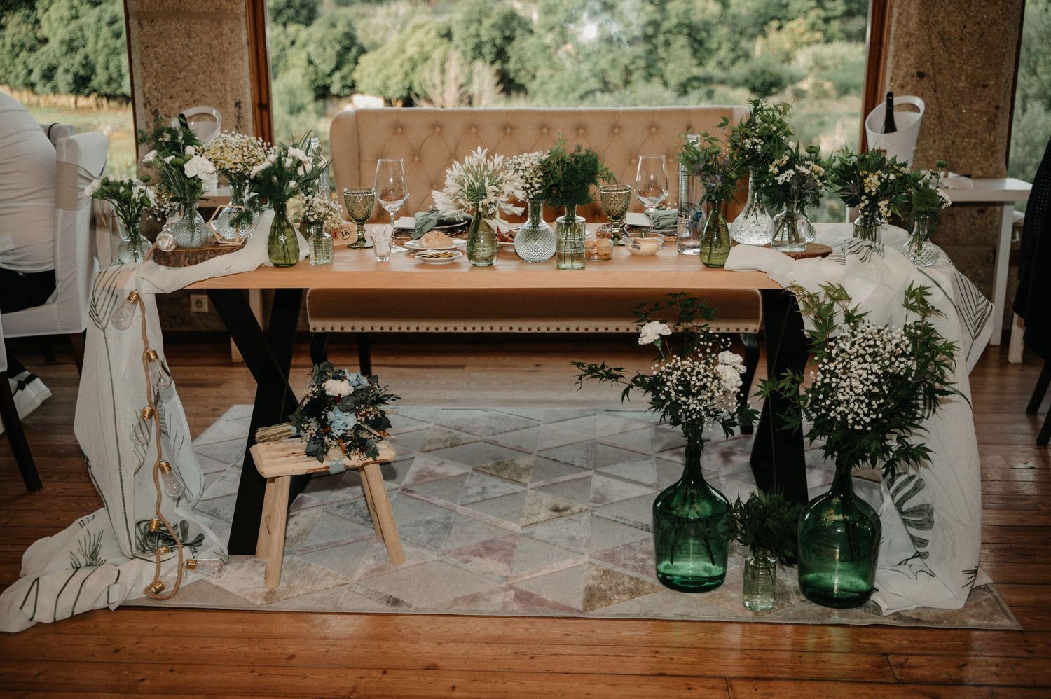 Elegant wedding reception decor featuring white floral arrangements and greenery with soft lighting and rustic elements.