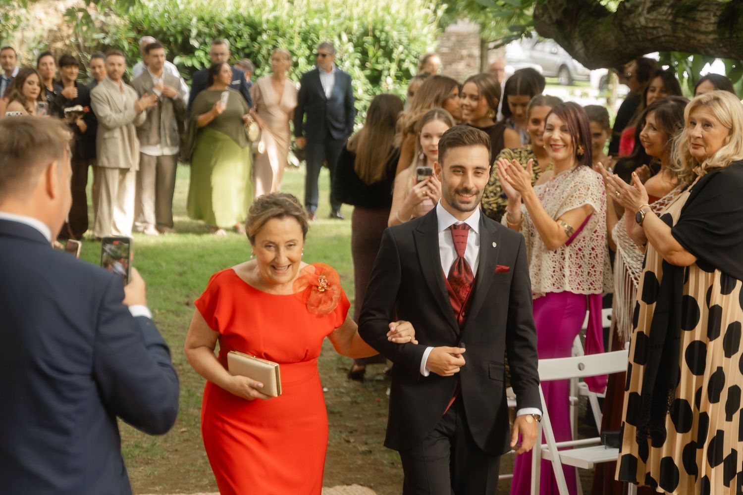 Guests mingling at an outdoor wedding reception with drinks in hand.