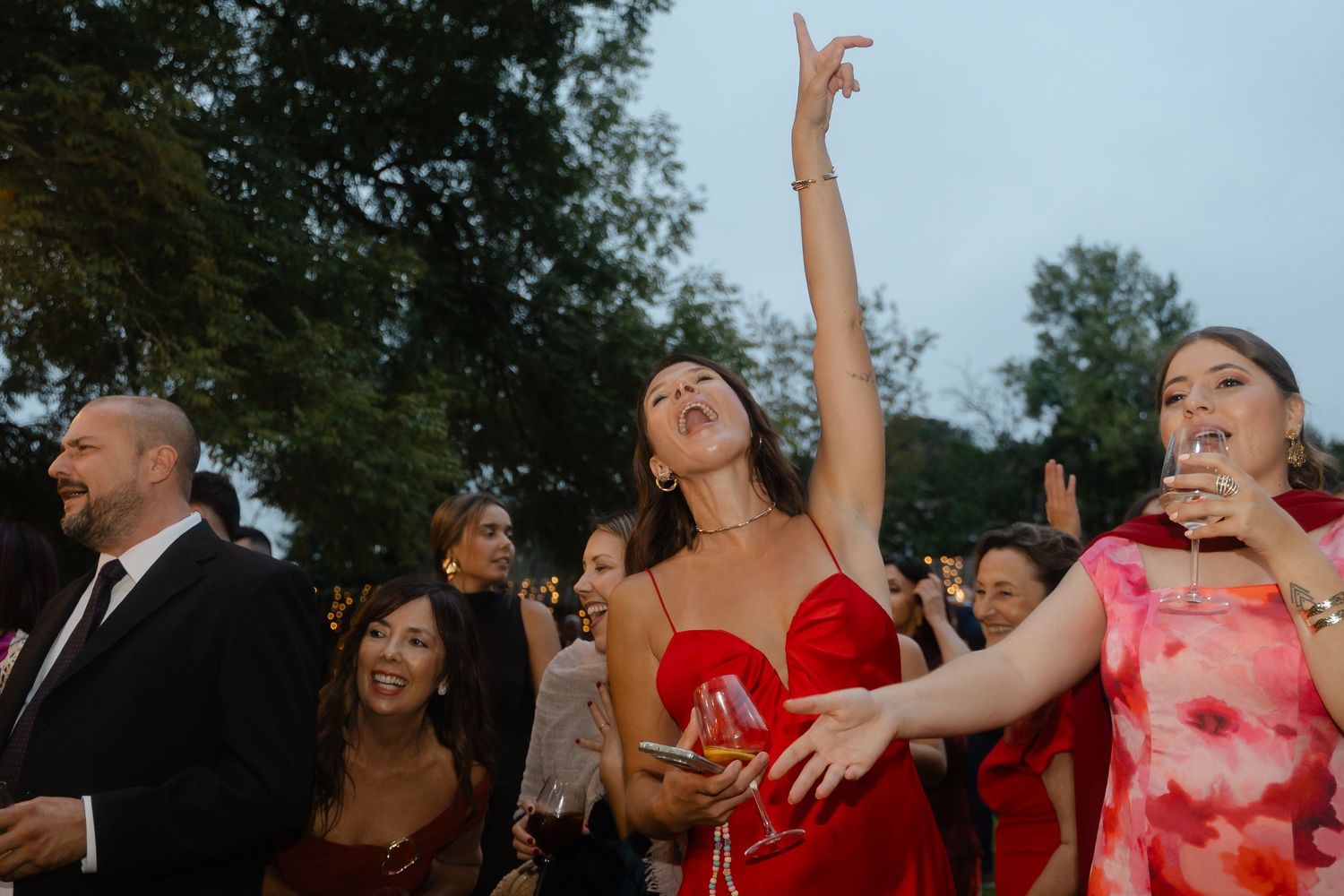 A group of wedding guests dancing and celebrating together at an outdoor reception.