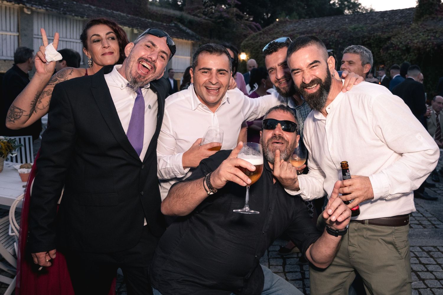 A group of friends pose together with drinks at a festive outdoor celebration.