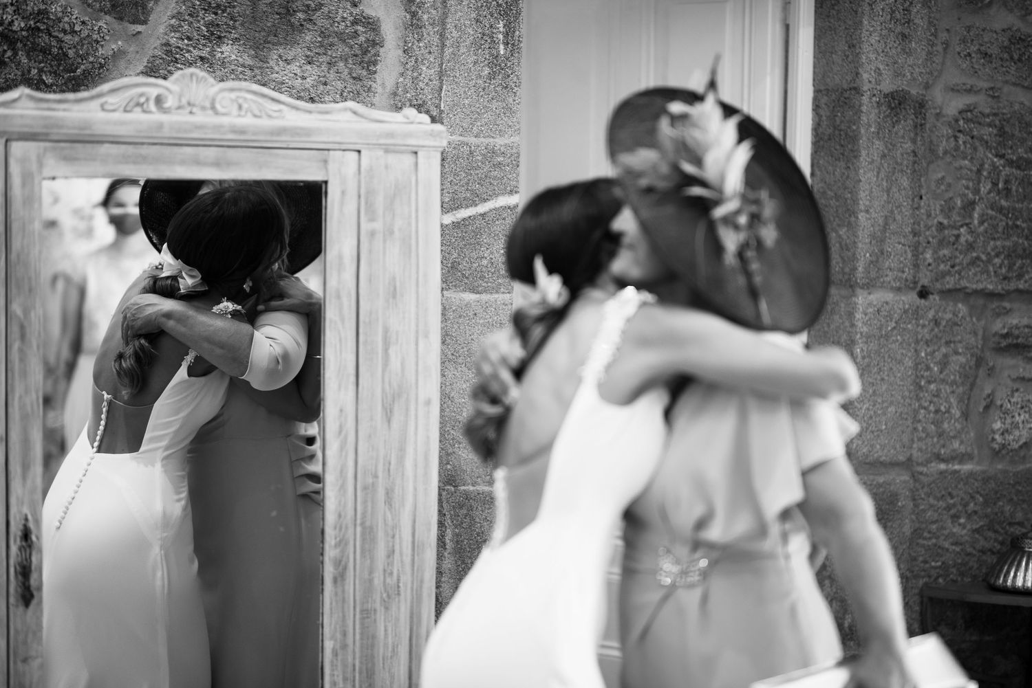 Black and white wedding photograph showing a bride looking in a mirror while getting ready for her ceremony.