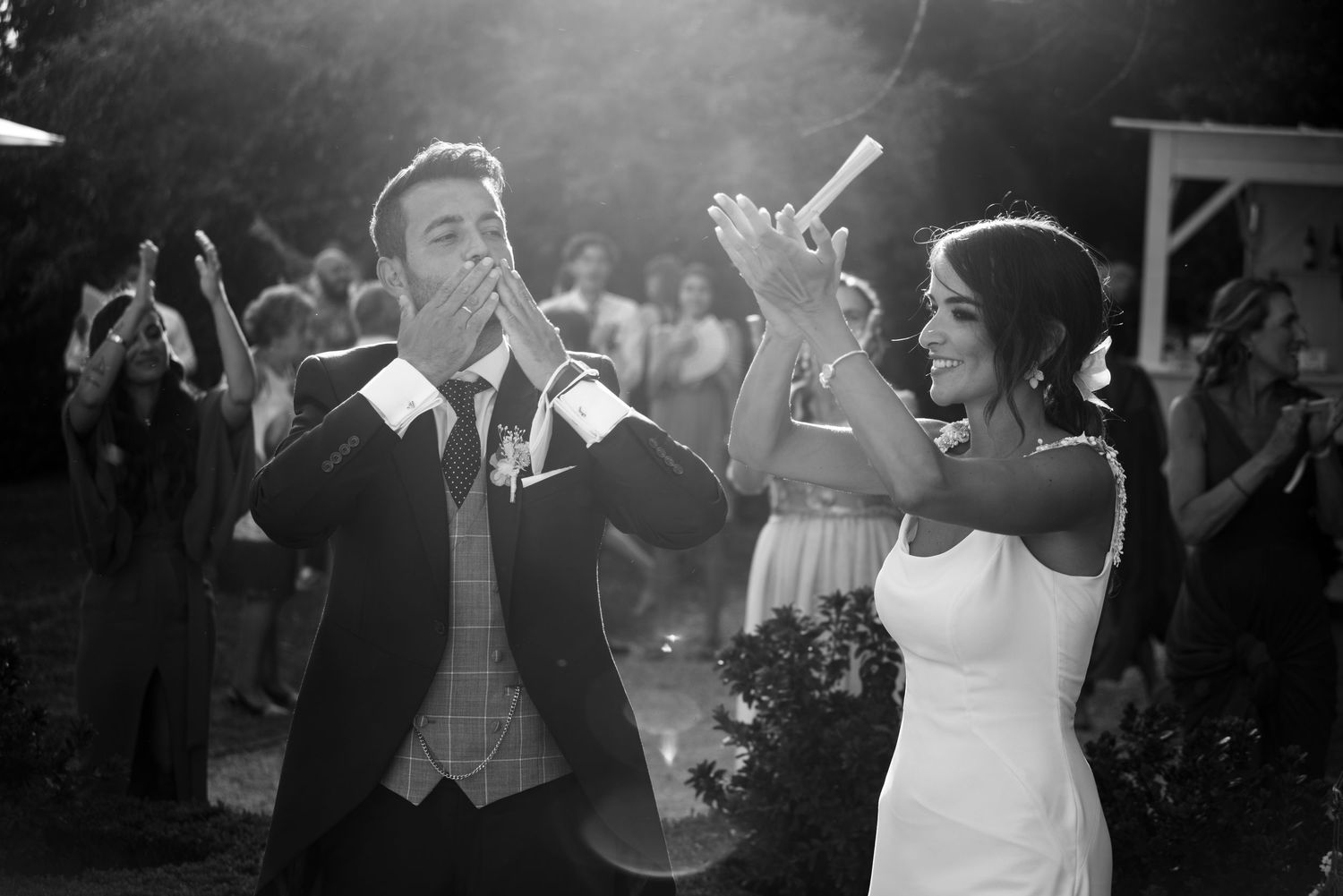 Black and white photo of wedding guests dancing and celebrating at an evening reception.
