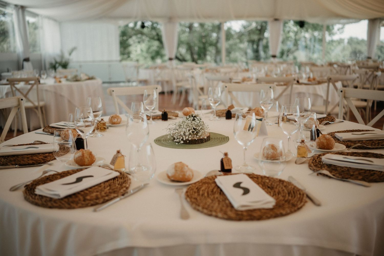 Elegant wedding reception tables decorated with gold charger plates, white linens, and soft draped fabric ceiling decor.