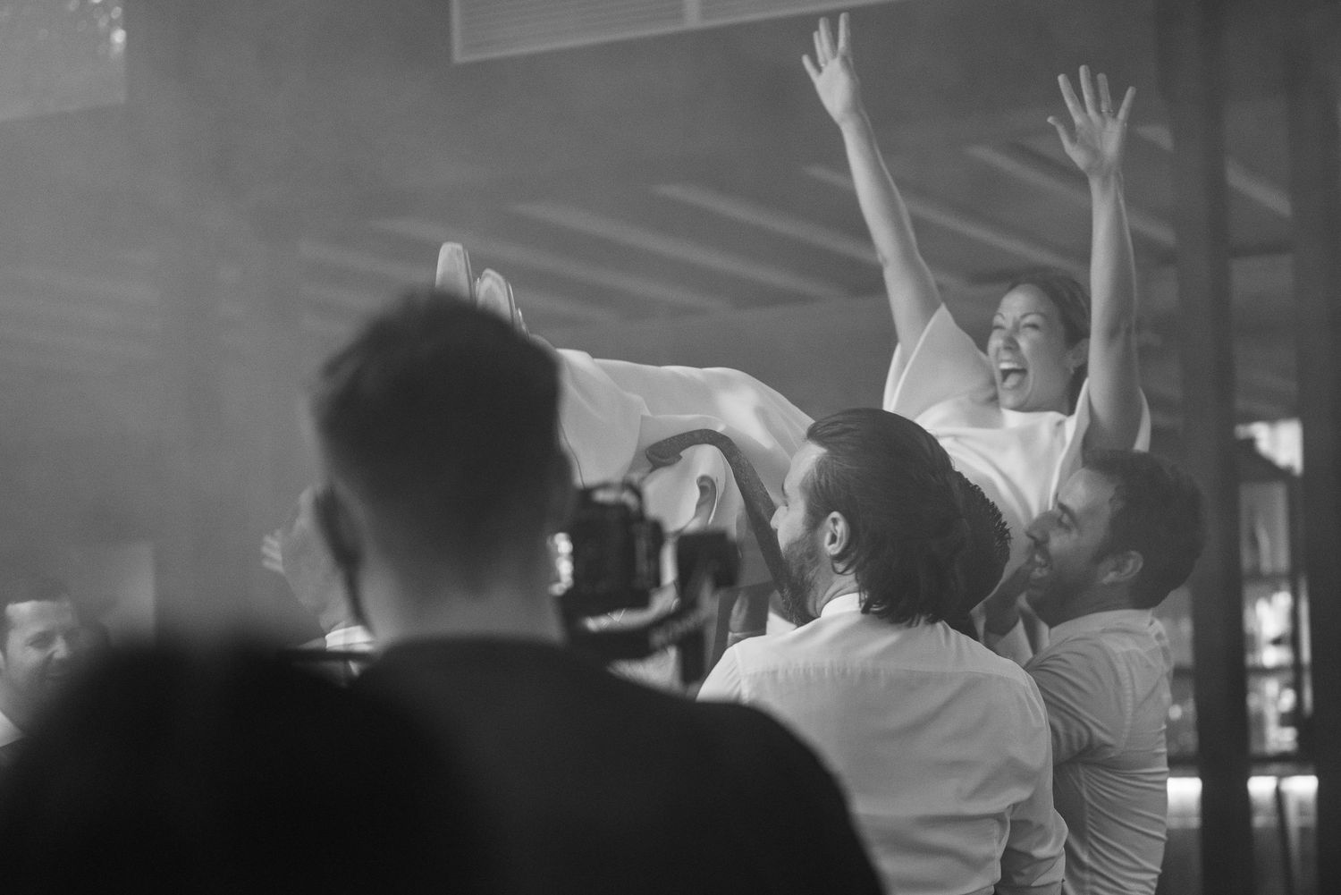 Black and white photo of concert audience with raised hands during performance.