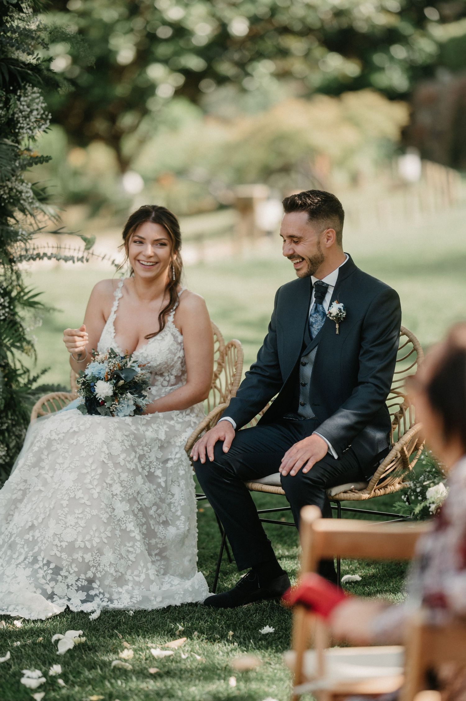 Couple sitting together during an outdoor garden wedding ceremony.