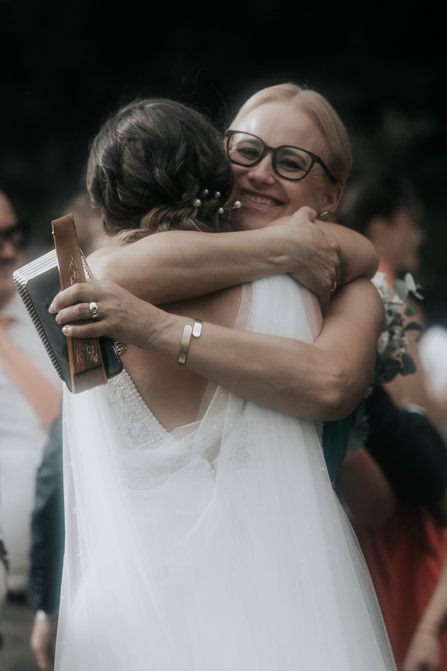 Emotional embraces shared between wedding party members wearing white dresses.