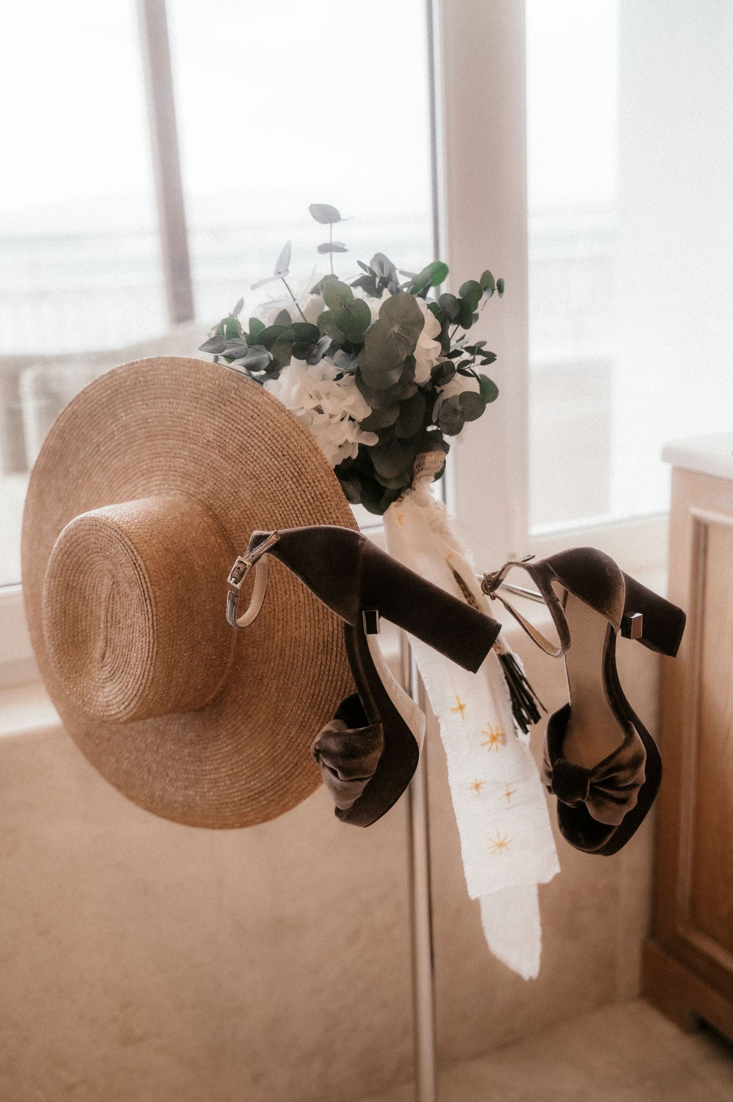 A series of four sepia-toned photos showing straw sun hats decorated with flowers and ribbons hanging on hooks.