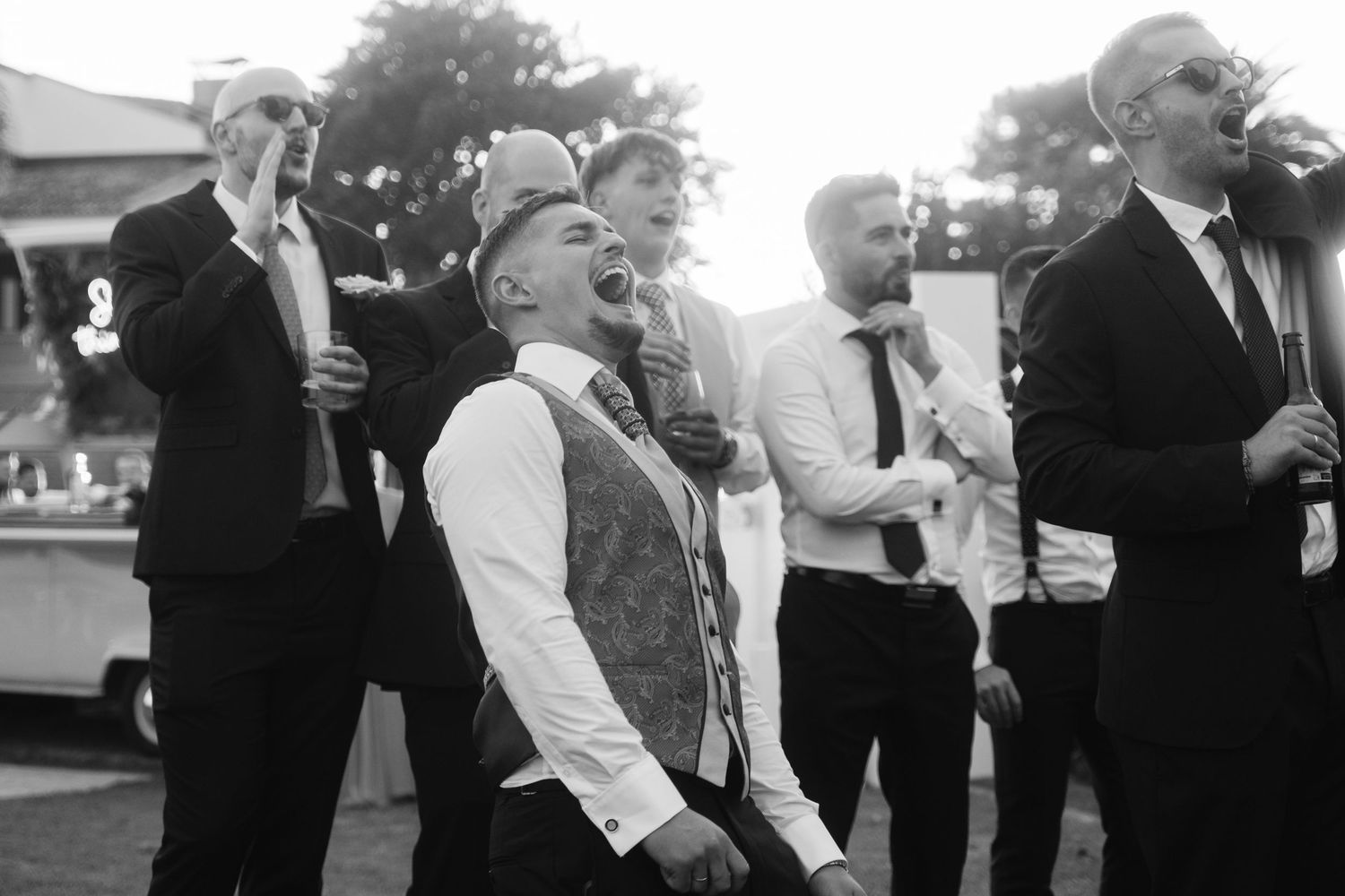 Wedding party celebrates outdoors during golden hour festivities.