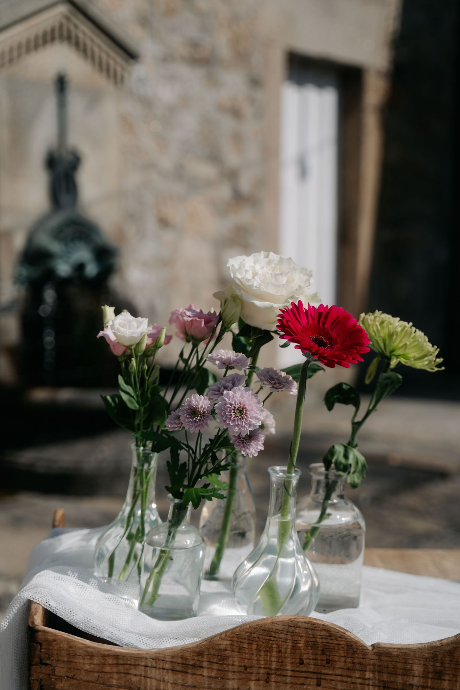 Fresh cut flowers in glass vases arranged on a wooden table with white linen creating an elegant centerpiece display.