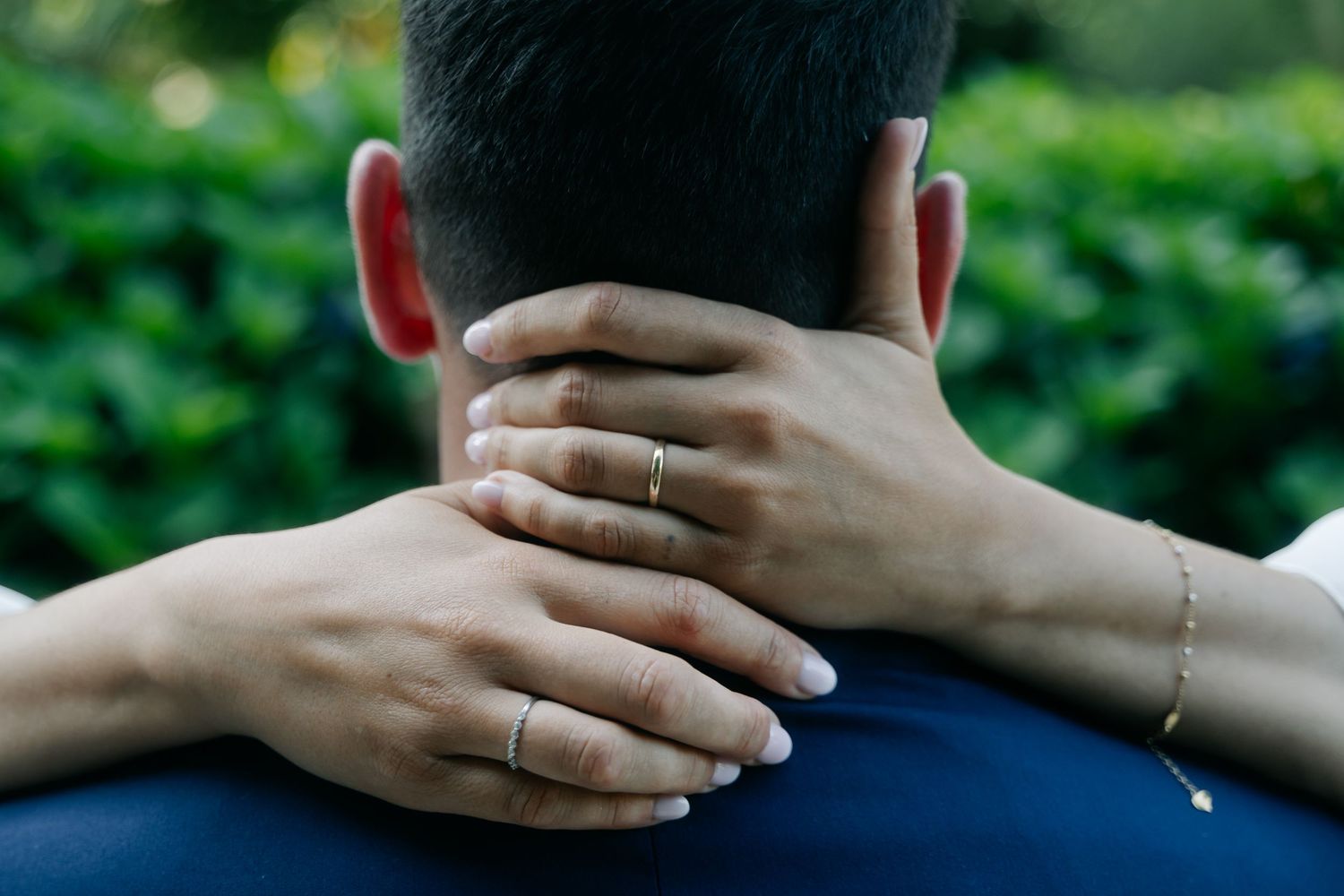 A series of hands gently touching the back of someone's neck in a comforting gesture against a green background.