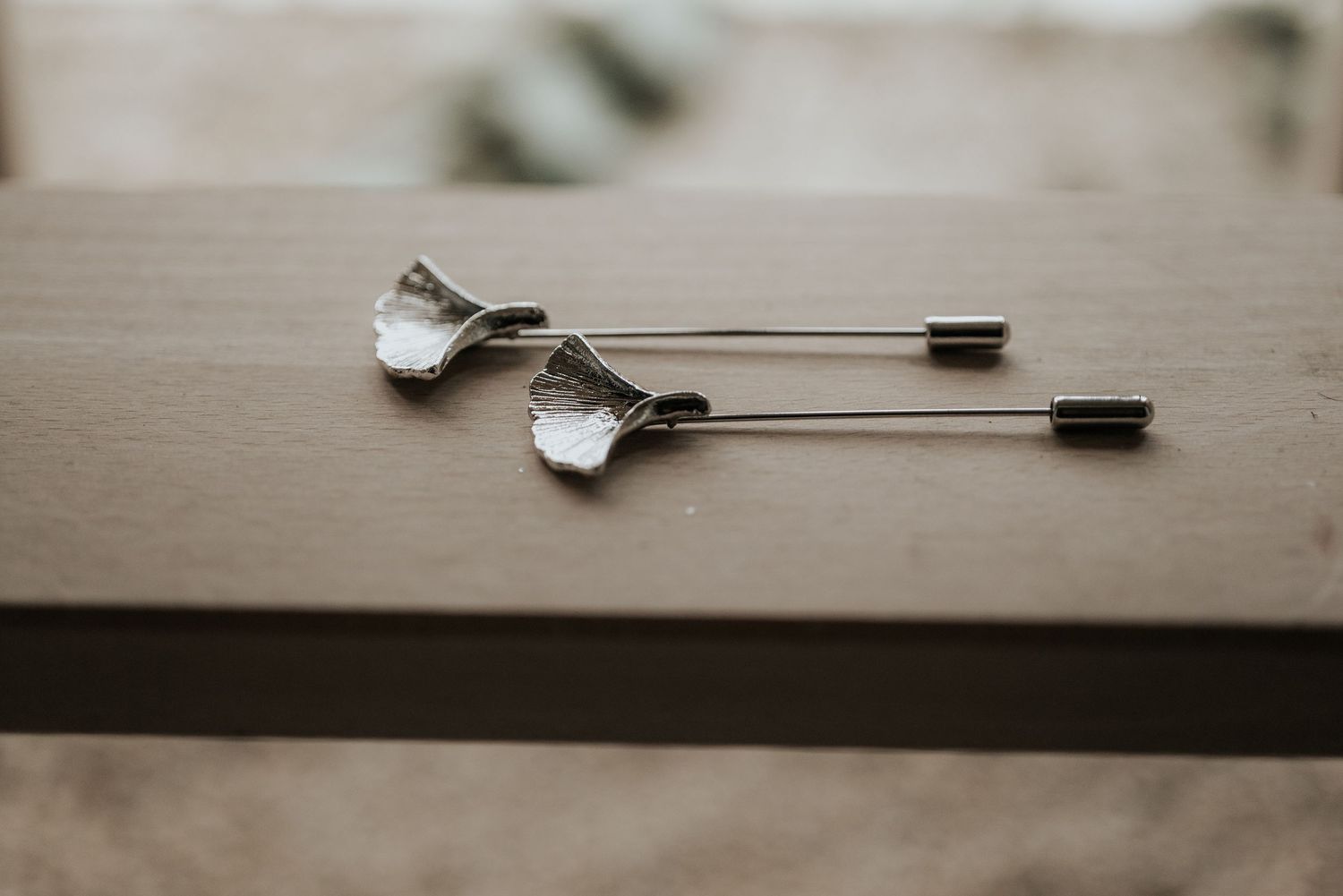 Two vintage silver spoons with decorative handles lying on a wooden surface in soft lighting.