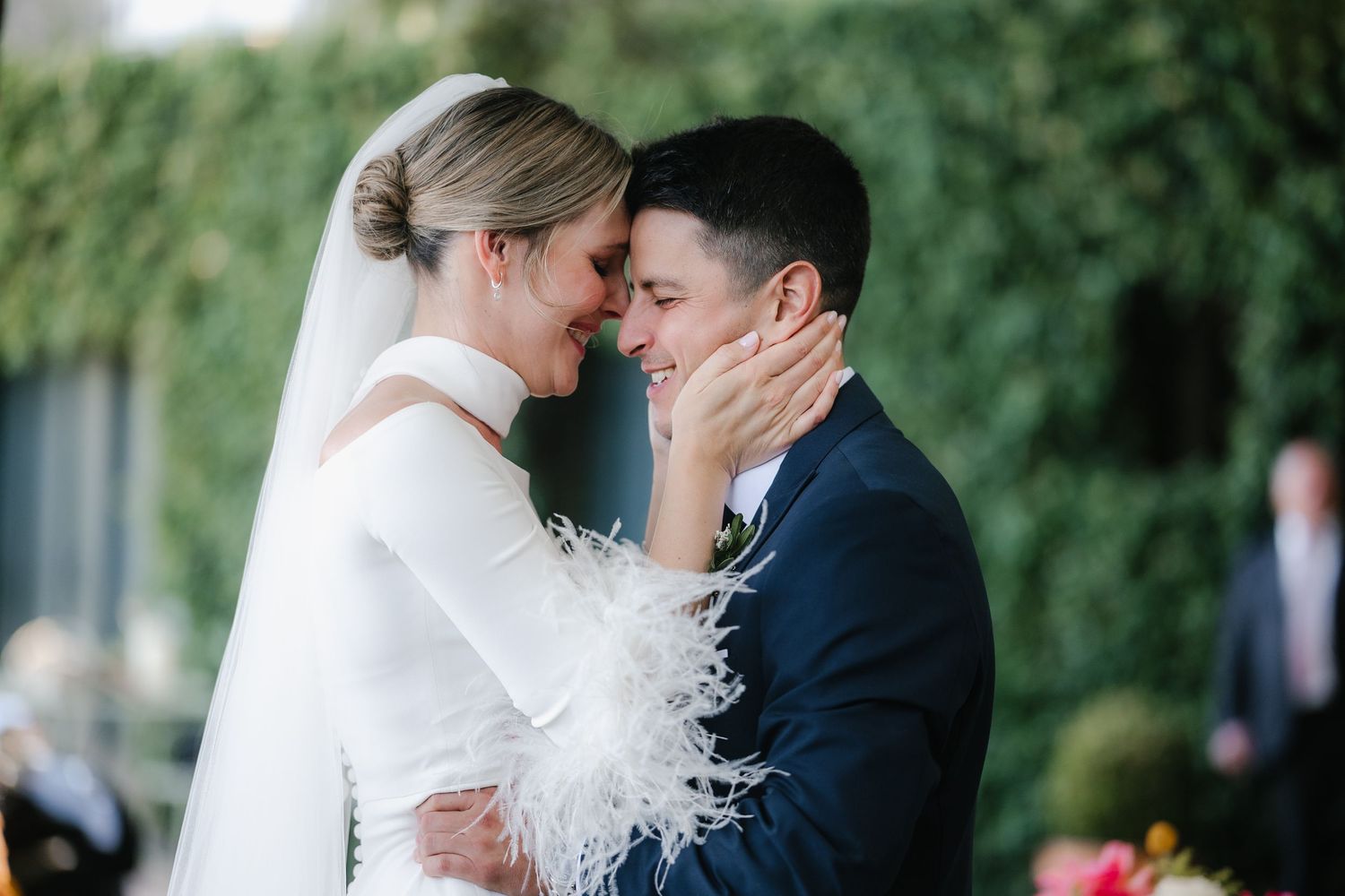 A tender moment between newlyweds against a backdrop of green foliage.