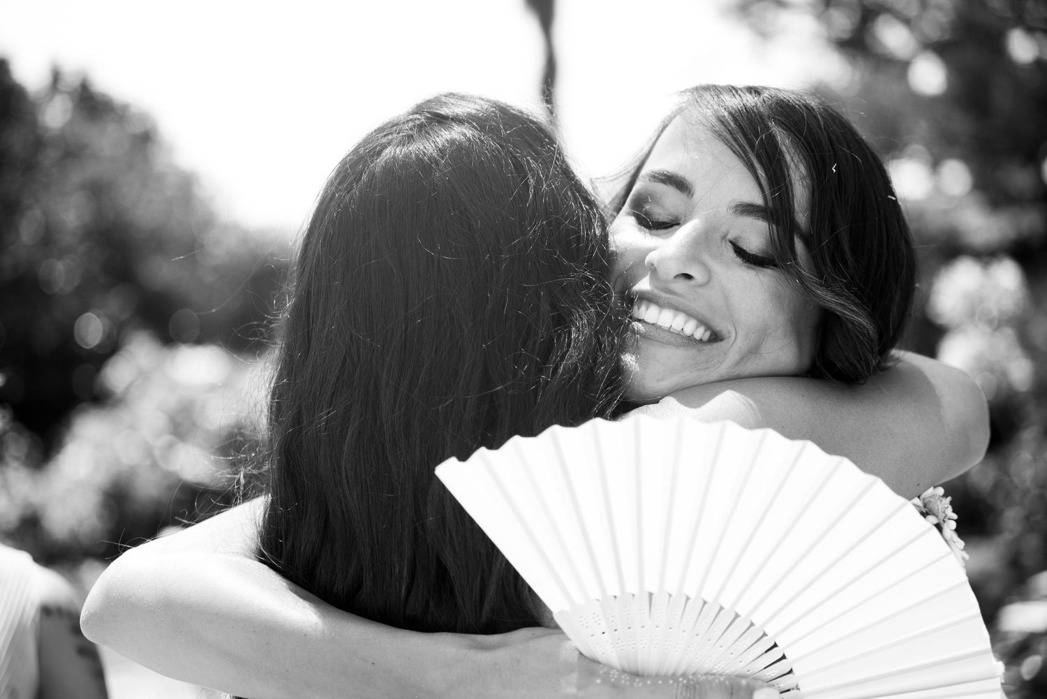 Wedding celebration captured in black and white with decorative fans and joyful moments.