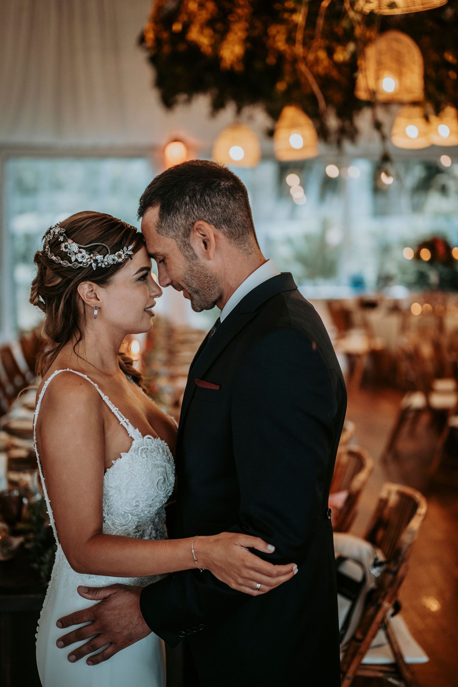 Romantic wedding couple shares intimate moments on their special day in a warmly lit reception venue.